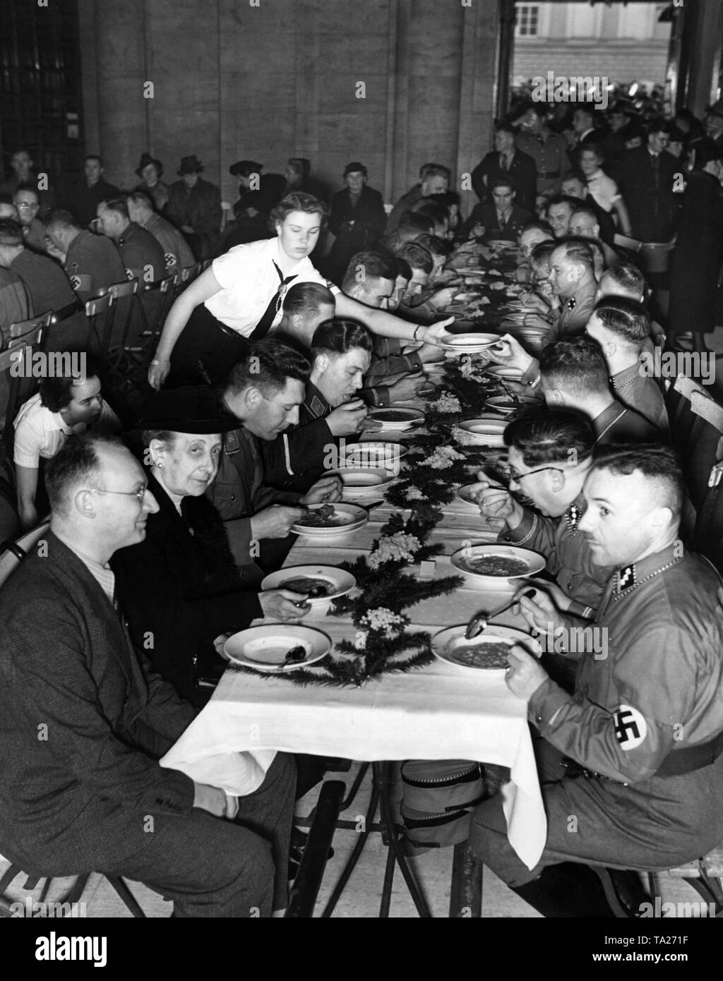SA Offiziere essen Eintopf nach ihrer Beförderung - symbolisch für das winterhilfswerk Propaganda - im Vorraum der Friedrich-Wilhelms-Universität (heute Humboldt-universität), als Gast der Ehre, die Mutter des getöteten SA Mitglied Harry Anderssen (vorne links). Stockfoto