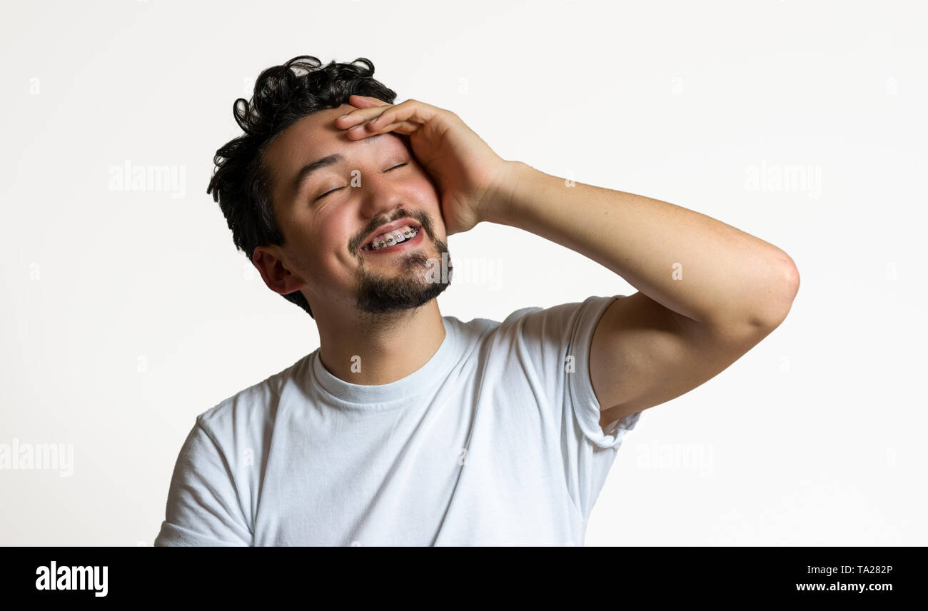 Porträt eines jungen Mannes mit Klammern lächelnd. Ein glücklicher junger Mann mit Klammern auf einem weißen Hintergrund. Stockfoto