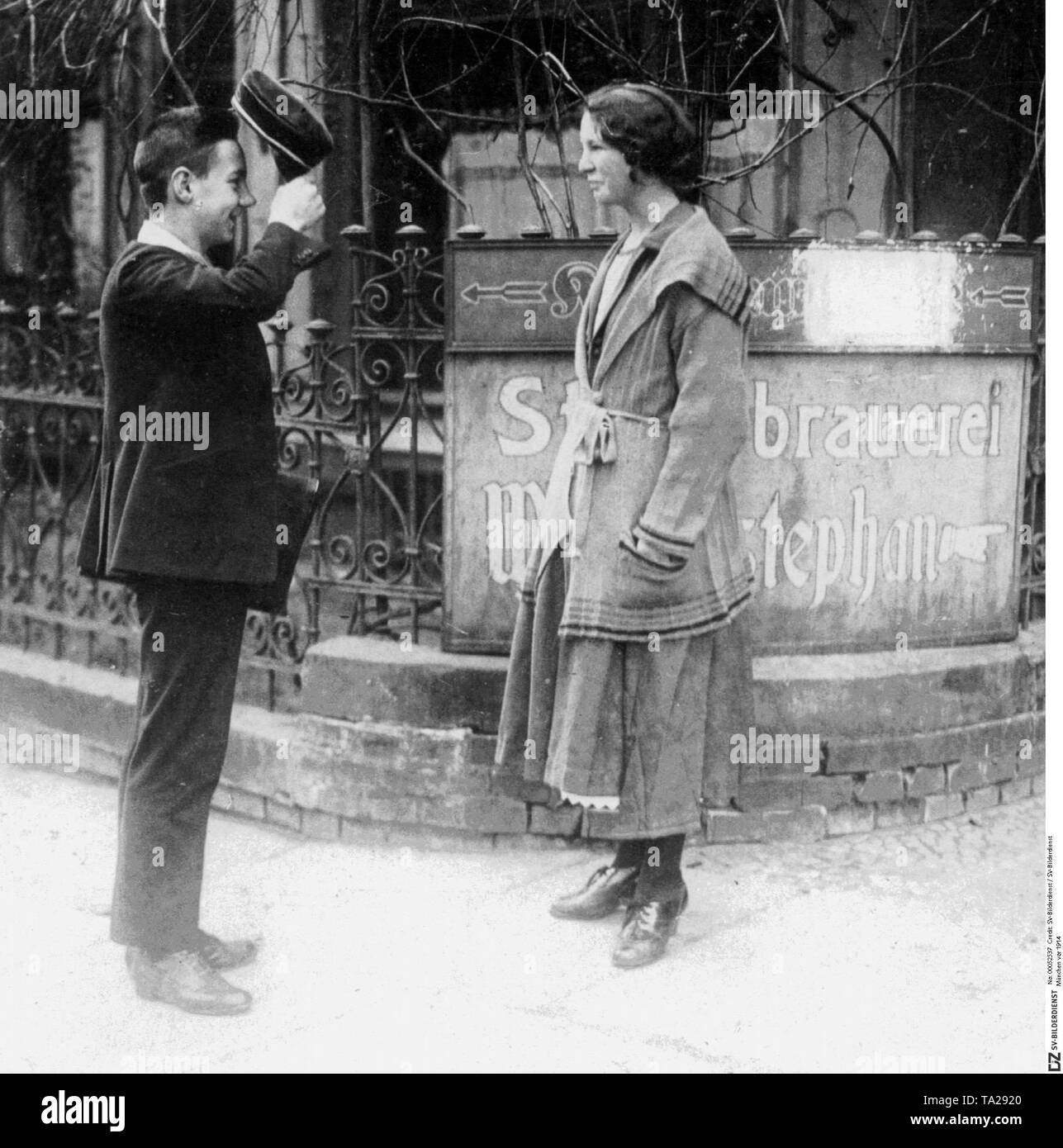 Ein High School Student trifft sich mit seiner Freundin für ein Rendezvous an einer Straßenecke in München. Im Hintergrund ist ein Zeichen der staatlichen Brauerei 'Weihenstephan'. Stockfoto
