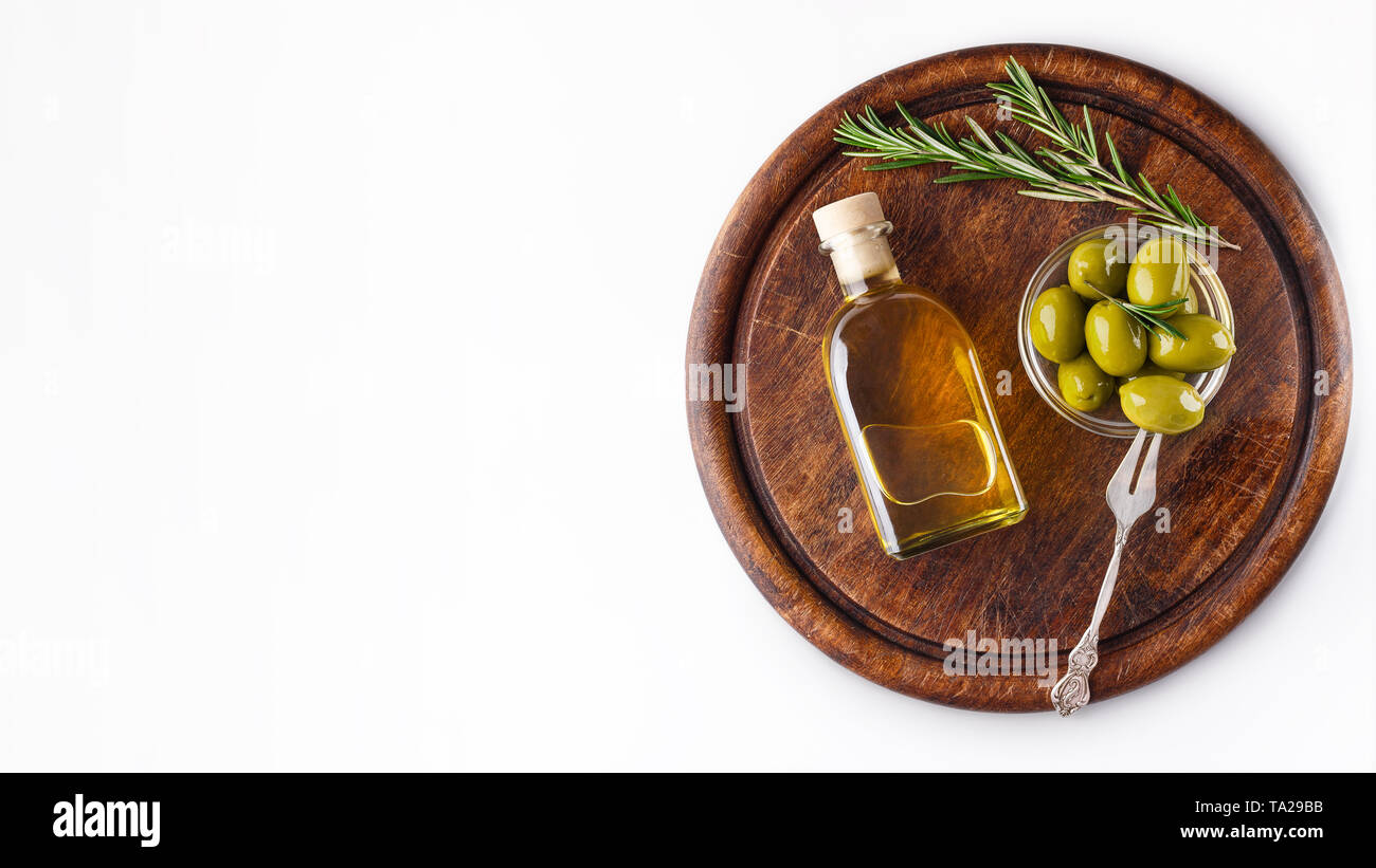 Olivenöl und grüne Oliven in Schale an Bord. Stockfoto
