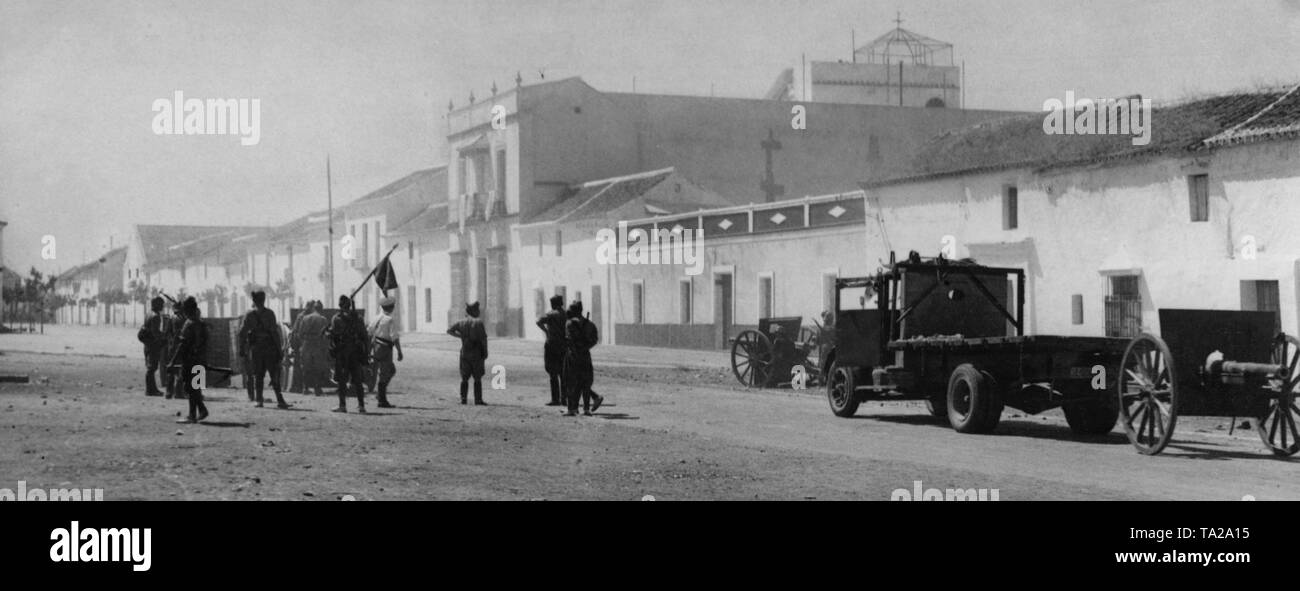 Foto von einem Quadrat, vermutlich in einem Vorort von Sevilla im Jahr 1936. Eine Gruppe von grenadiere bauen Haubitzen und Kanonen. Auf der rechten Seite, ein Lkw mit einer Bordkanone Beförderung. Stockfoto