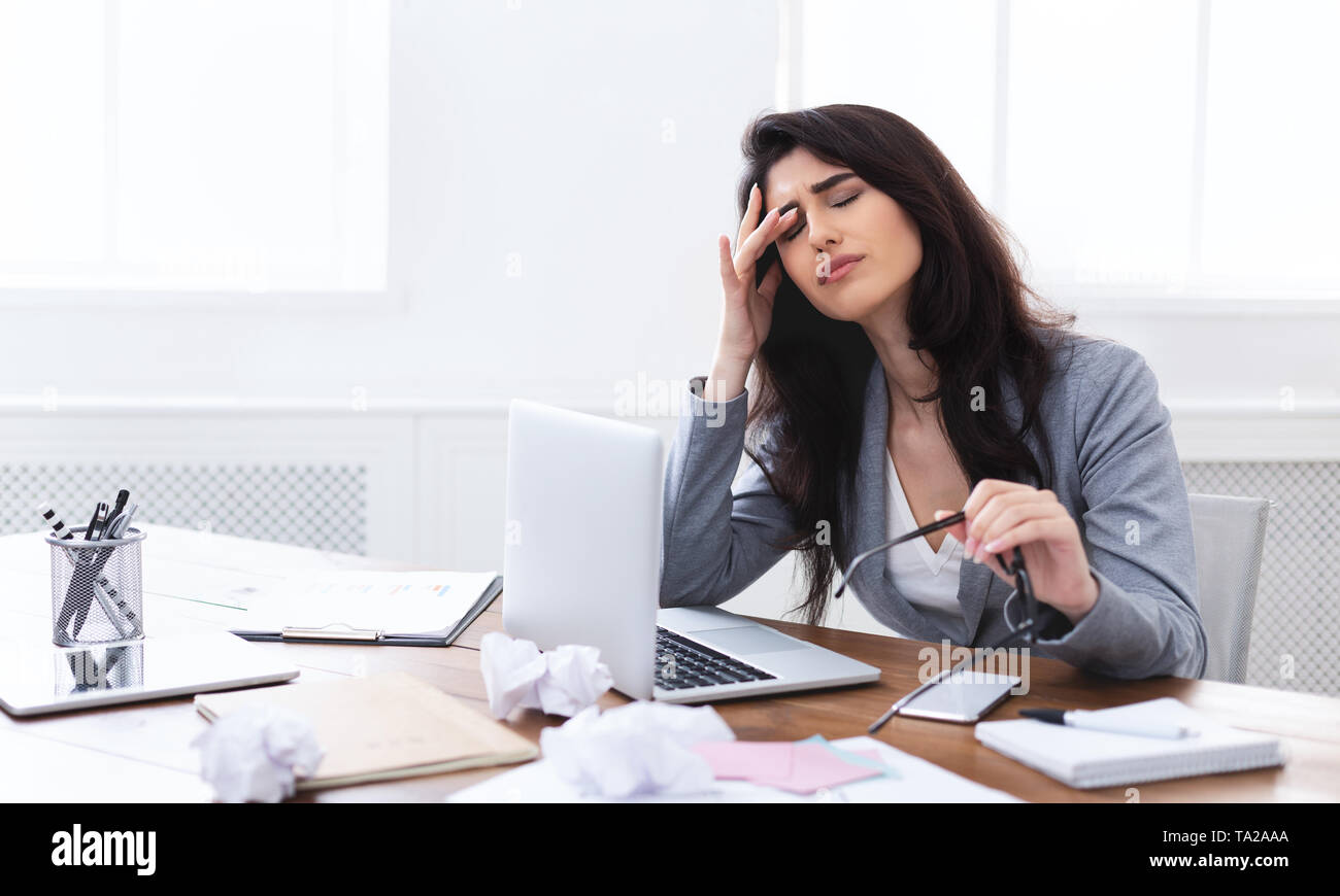 Müde und gestresst. Frustrierte Frau sitzt am Arbeitsplatz Stockfoto