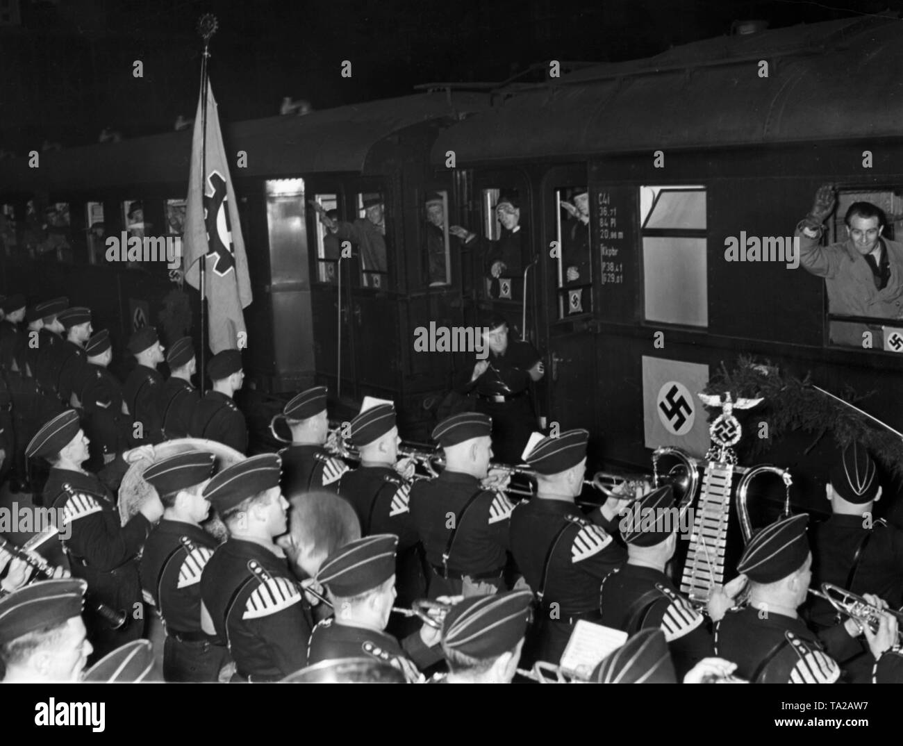 Nach dem Anschluss Österreichs, österreichischer Arbeiter an einer Deutschland Tour von der NS-Organisation "Kraft durch Freude" organisiert, hier bei der Ankunft am Hauptbahnhof München. In den Vordergrund, eine Band. Auf der linken Seite, eine Flagge der Deutschen Arbeitsfront. Stockfoto