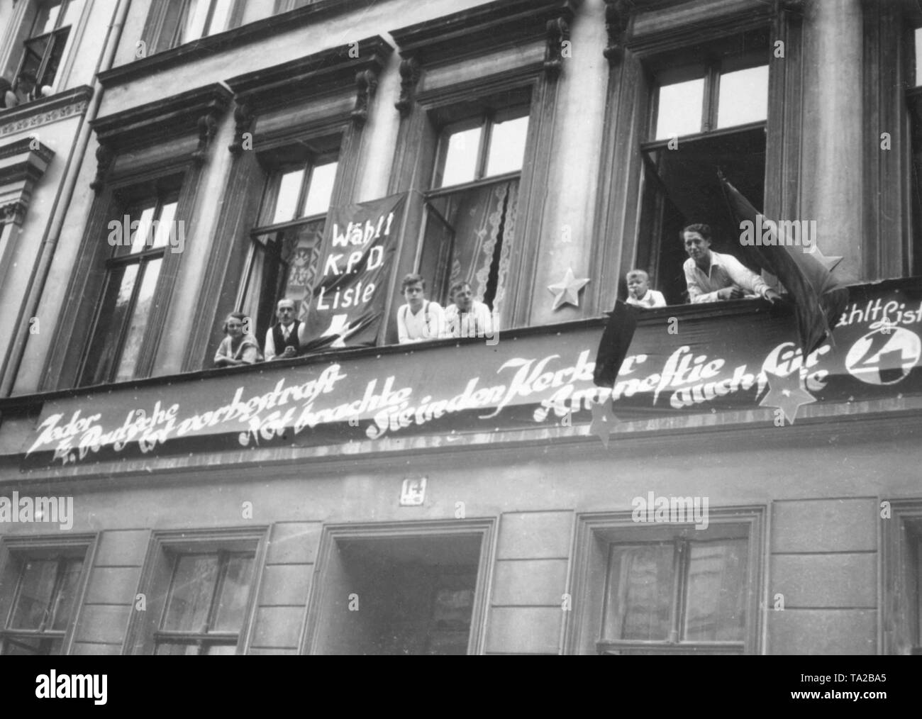 Für den Wahlkampf für den Reichstag die Wahl im Jahre 1930, Mitglieder der KPD eingerichtet diese Fassaden in der Koeslinerstrasse mit Fahnen, Sterne und Slogans. Die Inschrift lautet: "Jeder vierte Deutsche hat überführt worden. Elend hat sie in den Kerker gebracht, Amnesty auch für Sie." Die Bewohner beobachten das Geschehen auf der Straße. Stockfoto