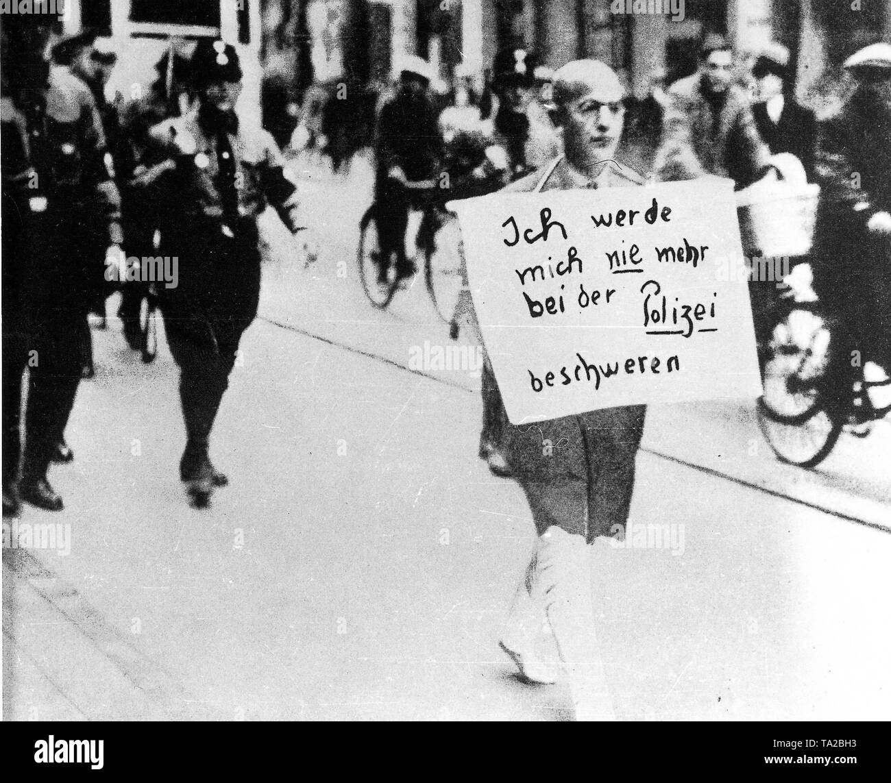 Dieses Foto von März 1933 aus München zeigt deutlich die fehlende Rechte jüdischer Bürger und der brutalen Zugriff der SS und SA nach der Machtübernahme durch die Nationalsozialisten im Januar 1933. Der Münchner jüdischen Rechtsanwalt Dr. Michael Siegel, der versuchte, in der Polizei gegen die Übergriffe der SA zu beschweren war durch die Innenstadt von München mit abgeschnittenen Hosen, barfuß, mit einem Schild um den Hals: "Ich nie beschweren bei der Polizei". Stockfoto