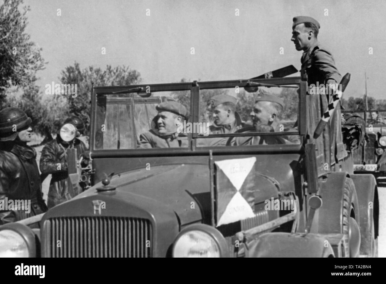 Foto der Befehl post Fahrzeug, Horch 901 (Kfz 15) Der Kommandant der Legion Condor, Major General Wolfram von Richthofen (in den Sitz des Treibers, neben ihm Stabsoffiziere). An der Front, die rote und die gelbe Wimpel der Legion Condor, der sich an der rechten Seite der Blinker der Wimpel der Stabschef. Richthofen ist ein Gespräch mit einem italienischen tank Commander in einer Lederkombi. Stockfoto