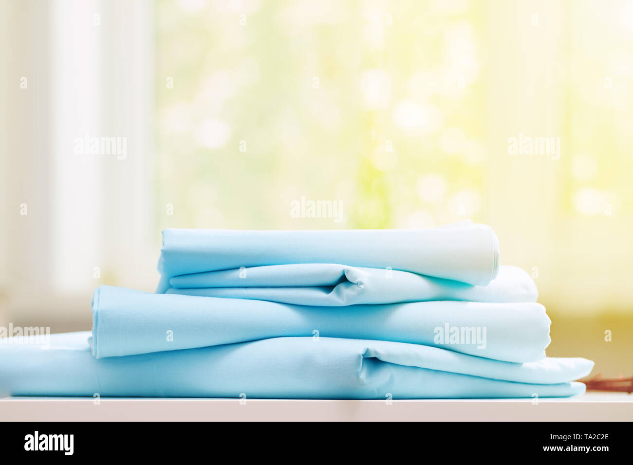 Closeup Stapel blau sauberes Bettzeug auf verschwommenen Hintergrund. Sonnenlicht aus dem Fenster. Stockfoto