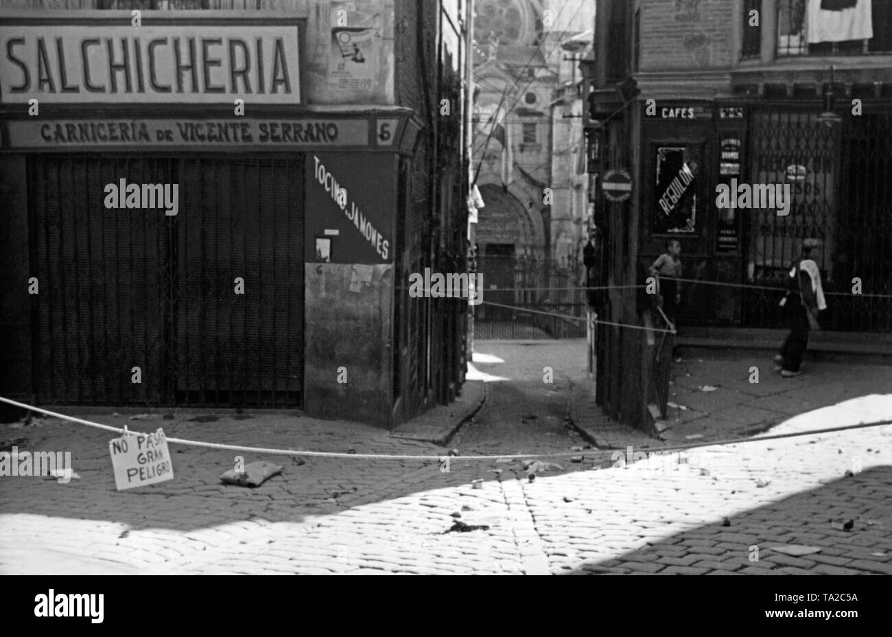 Eine straffe Linie und ein Schild (Inschrift: Keine Passage. Große Gefahr.) kennzeichnen den Beginn der Battle Zone in Toledo im Sommer 1936. Stockfoto