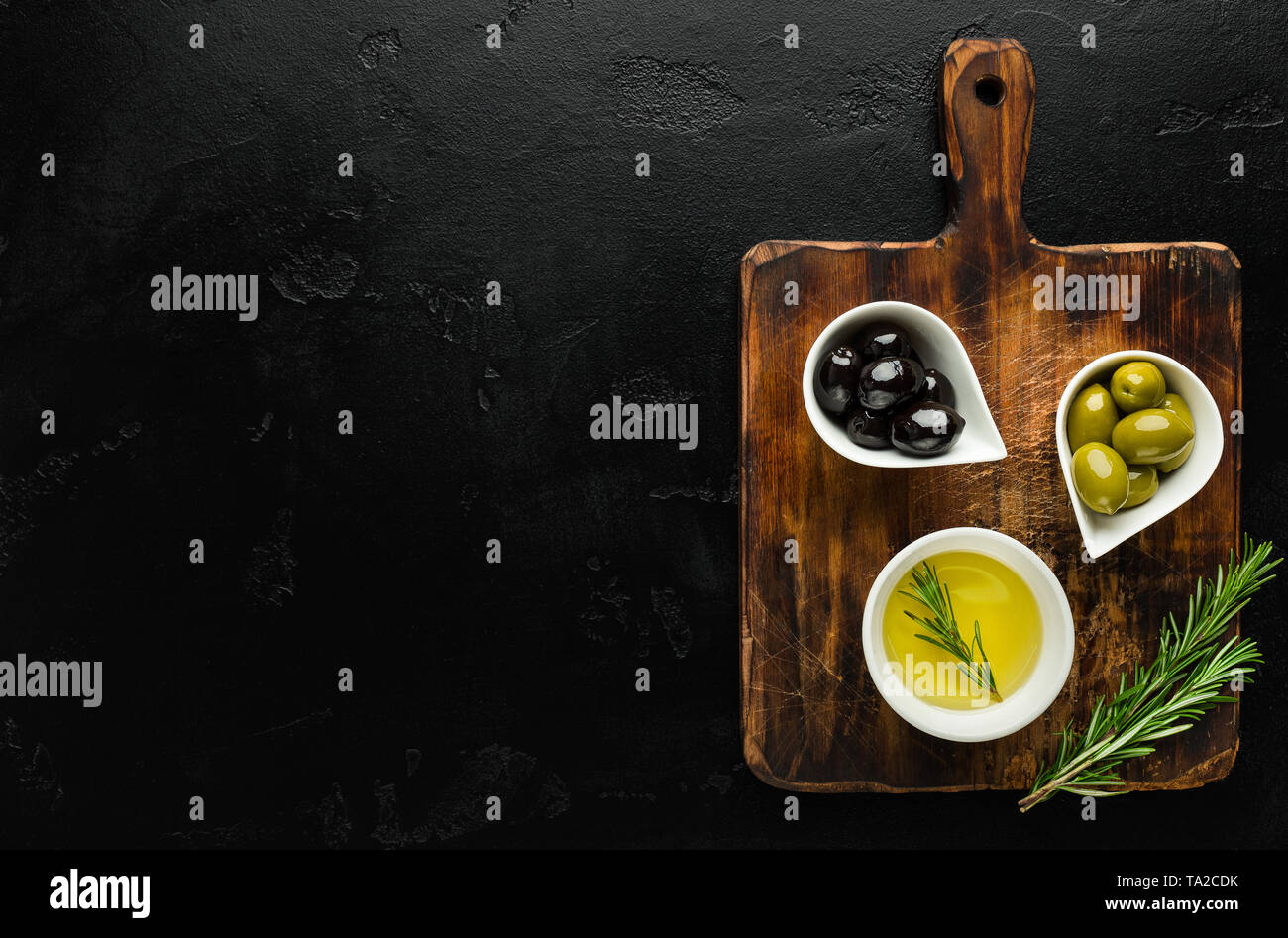 Olivenöl und Oliven in Schalen an Bord. Stockfoto