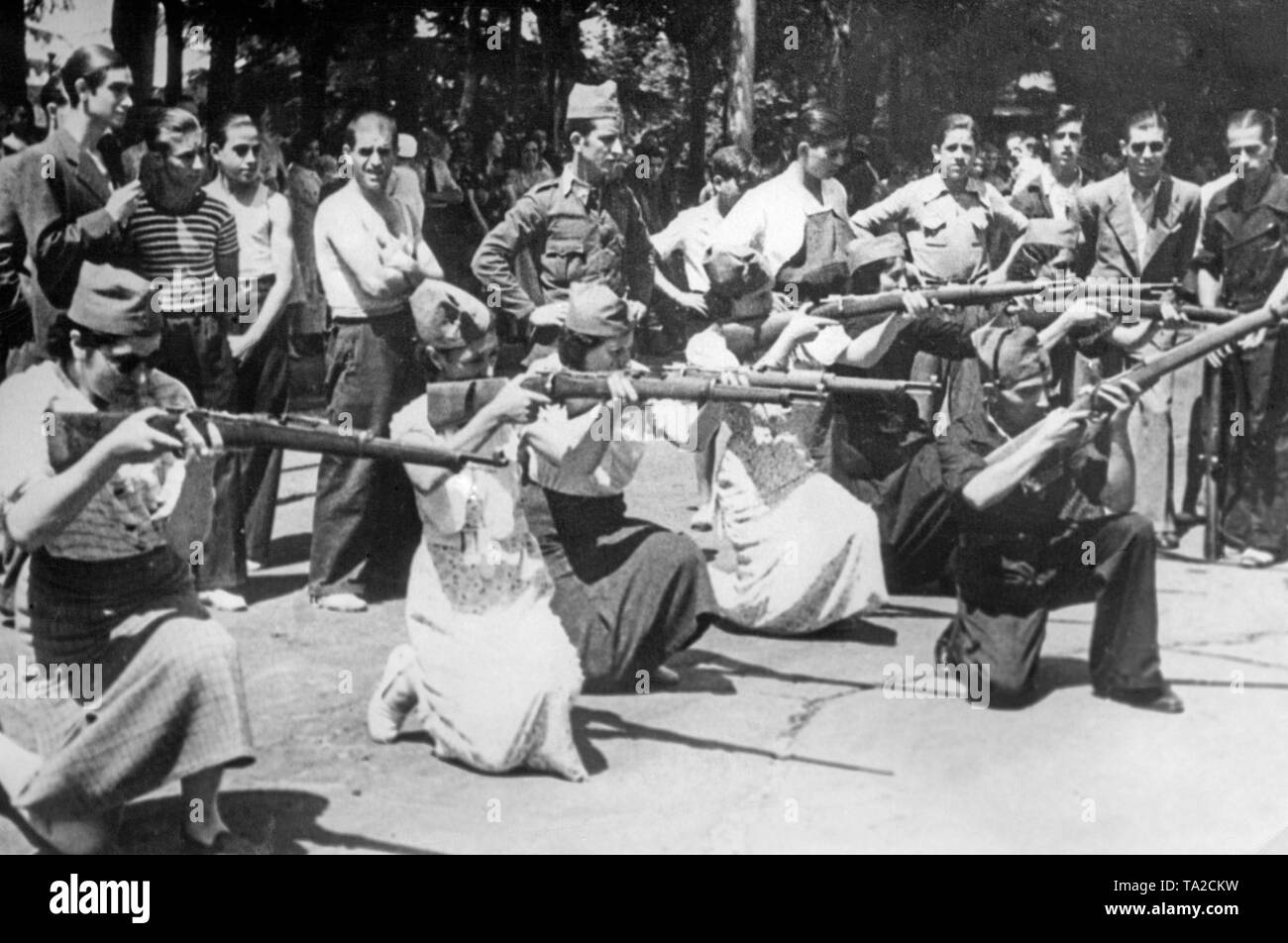 Foto von Frauen (mit militärischen gorillo Hüte) auf Waffen (Gewehr 98) von Republikanischen Ausbilder in Uniform während der Belagerung von der spanischen Hauptstadt des spanischen nationalen Truppen ausgebildet. Im Hintergrund, andere Freiwillige beobachten. Stockfoto