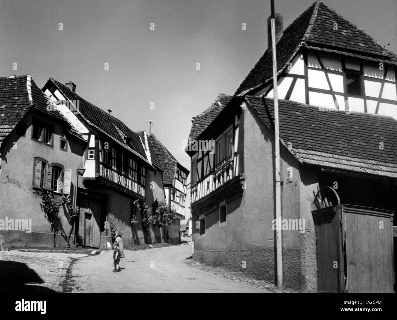 Zwei Kinder auf einem Dorf Straße mit Häusern mit Fachwerk oberen Etagen in Leinsweiler im Landkreis Suedliche Weinstrasse in Rheinland-Pfalz. Stockfoto