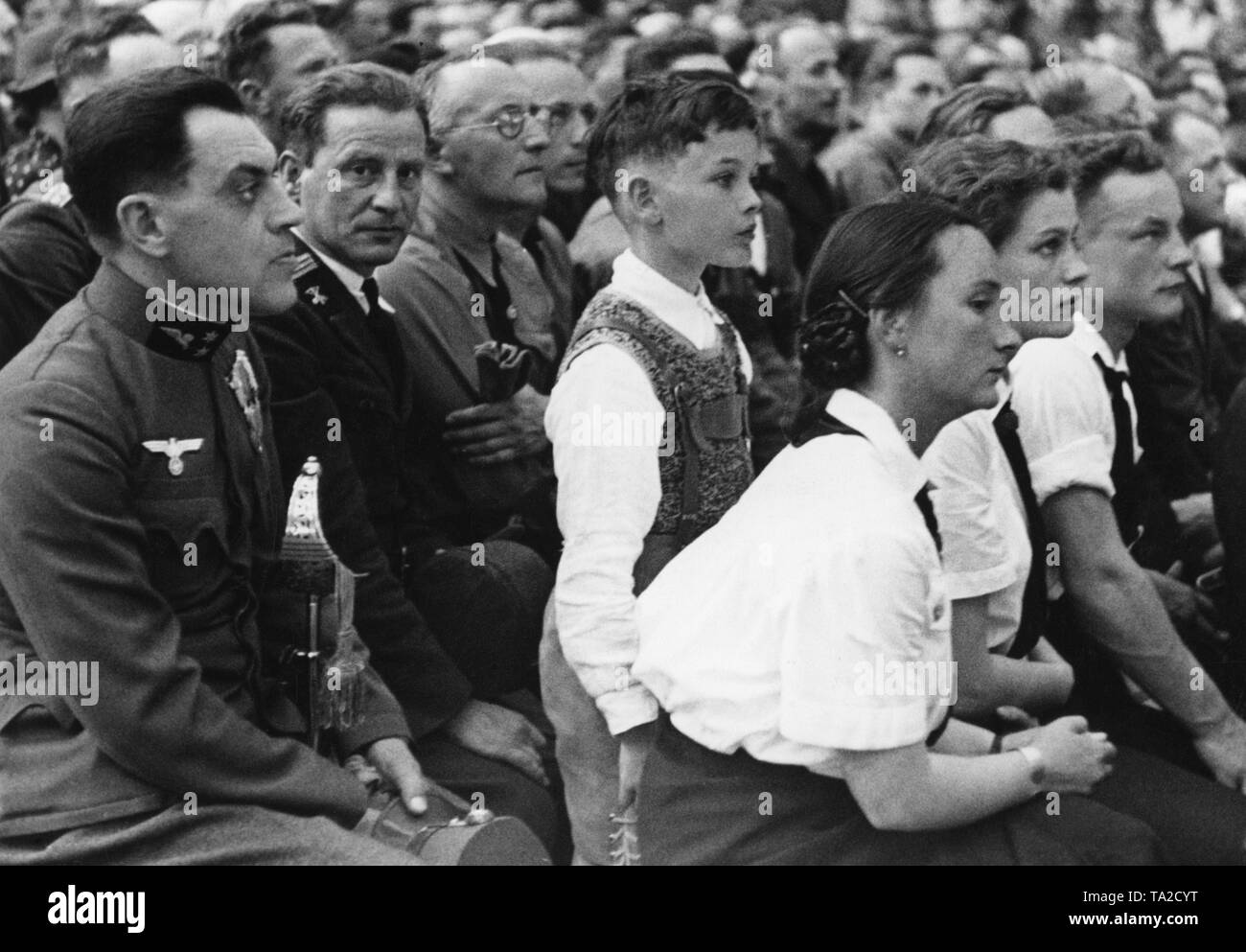 Adolf Hitler eine Rede in der Maschinenhalle Weitzer in Graz. Nach der Annexion Österreichs an das Deutsche Reich, die Nationalsozialistische Diktator besucht österreichischen Städten. Auf der linken Seite, ein Soldat, der bereits den Deutschen Hoheitszeichen trägt, der Adler mit dem Hakenkreuz, auf seine österreichische Uniform. Stockfoto