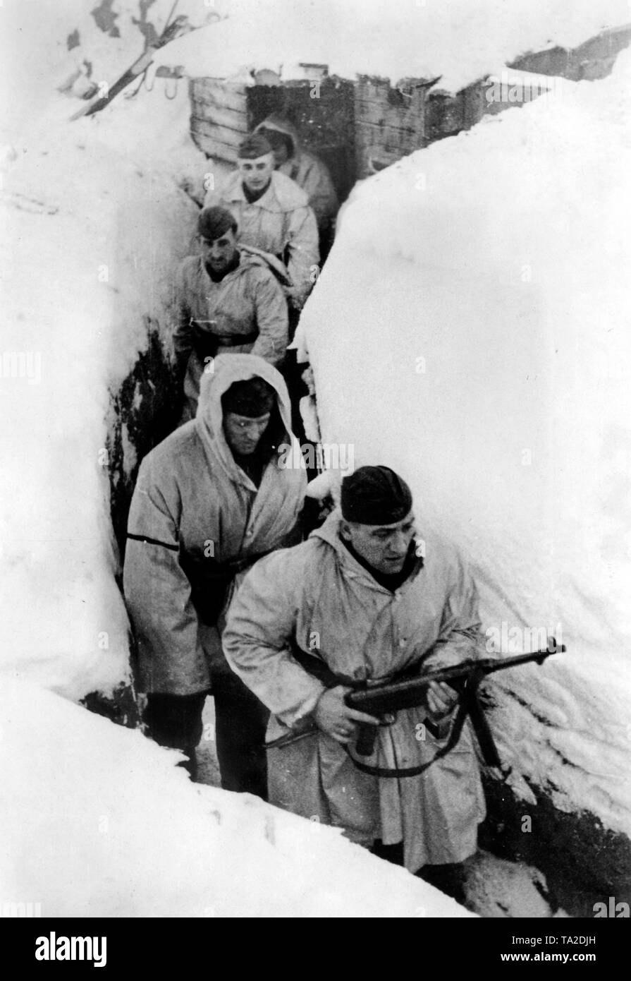 Deutsche Soldaten im Winter camouflage Kleidung laufen durch einen Graben südlich vom See Ilmensee. Die in der vorderen hält eine Maschinenpistole 40 an der highport. Foto der Propaganda Firma (PK): kriegsberichterstatter Etzold. Stockfoto