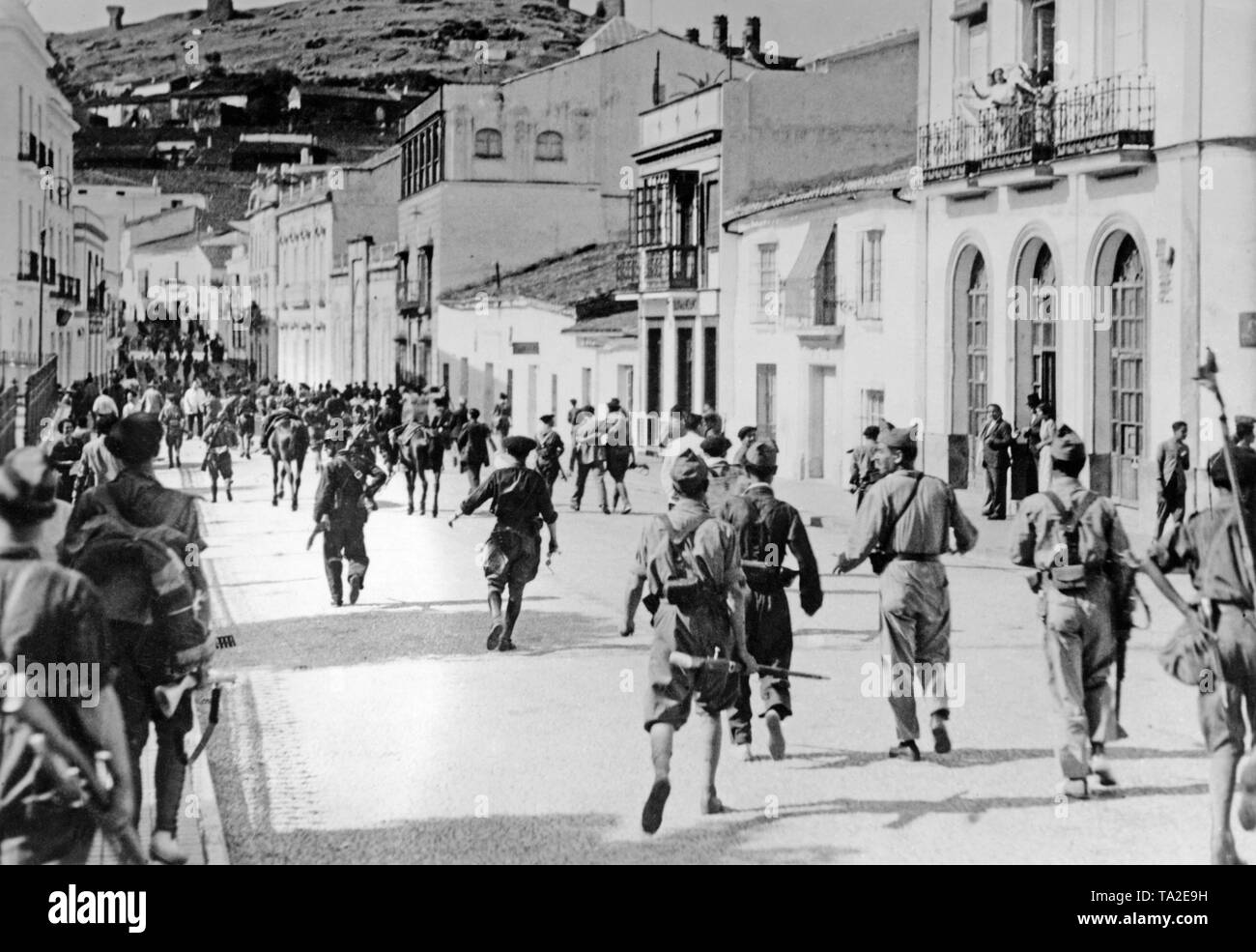 Foto von Marching - in spanischen Soldaten in Huelva, Andalusien, ein paar Wochen nach Ausbruch des Spanischen Bürgerkriegs im Sommer 1936. Bewohner willkommen die einfallenden Truppen von den Balkonen. Stockfoto