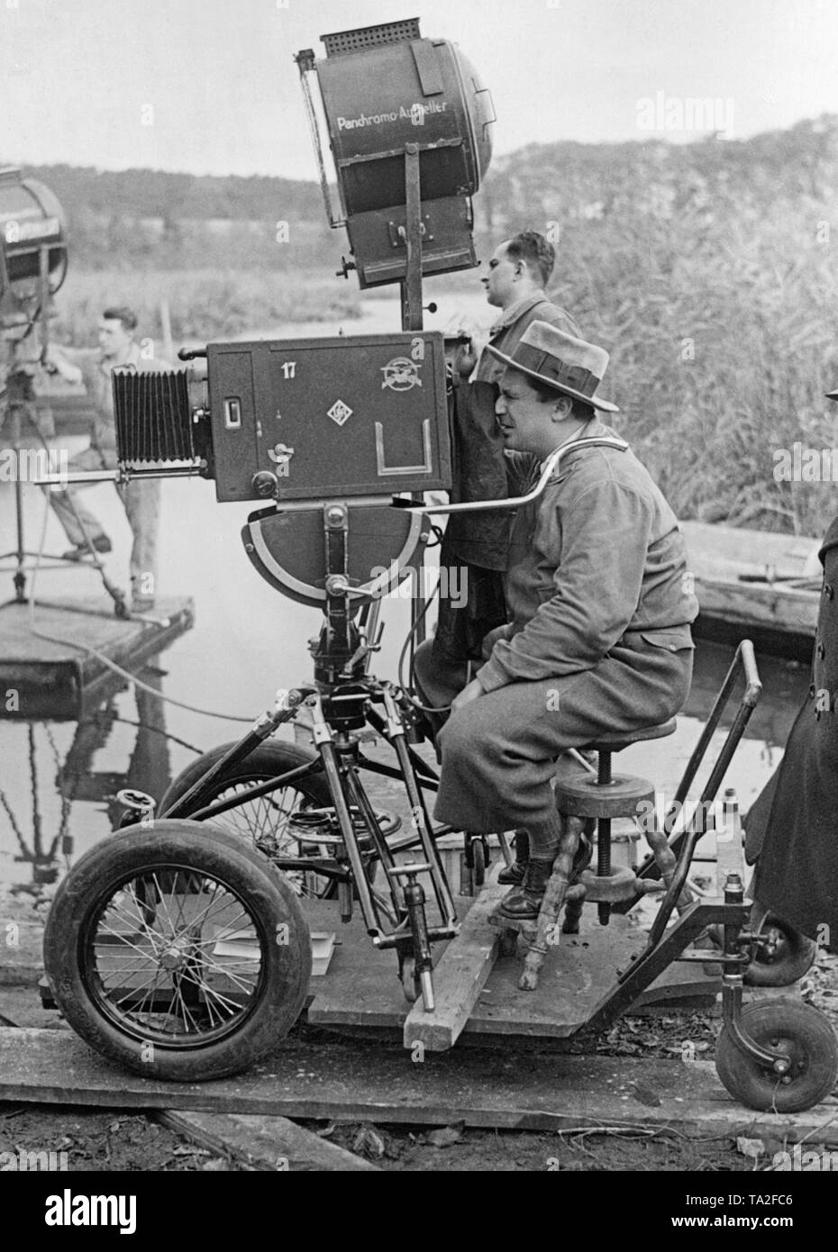 Foto von einem Kameramann Shooting der Film "Der Zigeunerbaron", unter der Regie von Karl Hartl. Der Kameramann sitzt auf ein vierrädriges Fahrzeug auf Schienen betrieben. Die Kamera selbst ist auch dieses Fahrzeug mit einem Stativ montiert, so dass sie mobil sind. Stockfoto