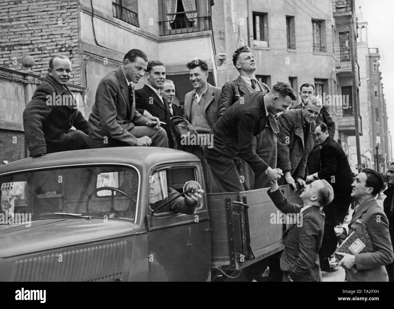 Foto von einer Gruppe von ausscheidenden Soldaten der Legion Condor auf der Ladefläche eines Opel Blitz Lkw nach dem Ende des Spanischen Bürgerkriegs (April 1939) Kurz vor ihrer Abreise im Mai, 1939. Die Soldaten sind das Tragen ziviler Kleidung, die an sie übergeben wurden, bevor Sie nach Hause gereist. Andere Soldaten nehmen Abschied von ihren Kameraden. Stockfoto