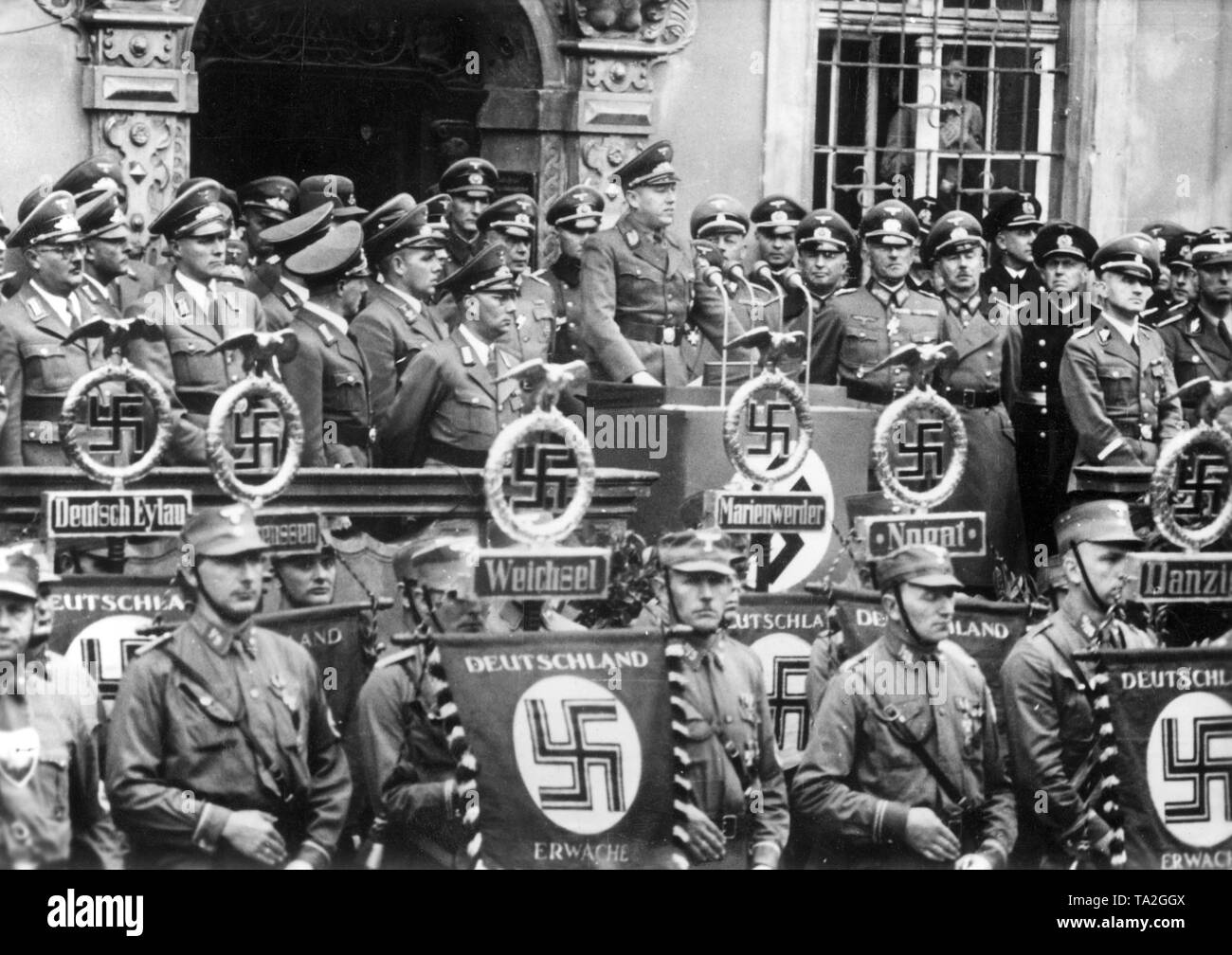NSDAP-Gauleiter und Gouverneur Albert Forster ist eine Rede an einer Nationalsozialistischen Kundgebung anlässlich des einjährigen Bestehens der deutschen Invasion in Polen. Auf der Hakenkreuzfahnen auf die Standards: "Deutschland wecken". Es ist ein standard mit einem Hakenkreuz für jede der Städte, Deutsch-Eylau, Weichsel, Flu Nogat, Marienwerder und Danzig. Stockfoto