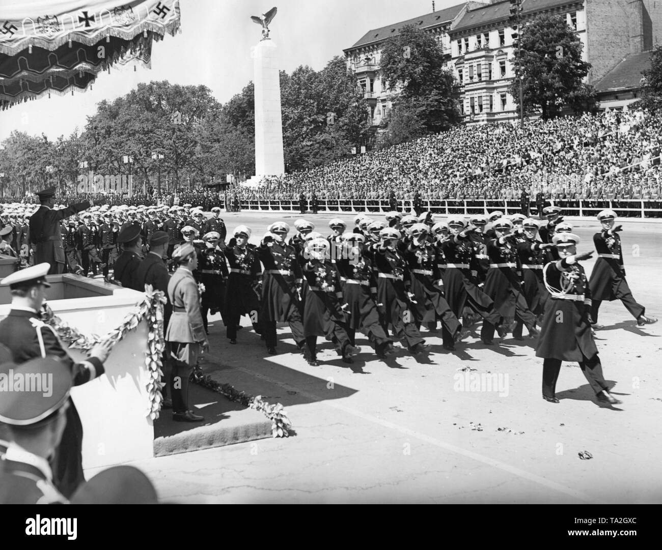 Foto eines marine Formation (die Offiziere geben den Hitlergruss) marschieren vor der Offiziere der Wehrmacht und Führer, Adolf Hitler (unter einem Vordach), die auf der Parade der Legion Condor auf der Ost-West-Achse (ehemalige Chalottenburger Chaussee, heute Straße des 17. Juni) vor der Technischen Universität am 6. Juni 1939. Stockfoto