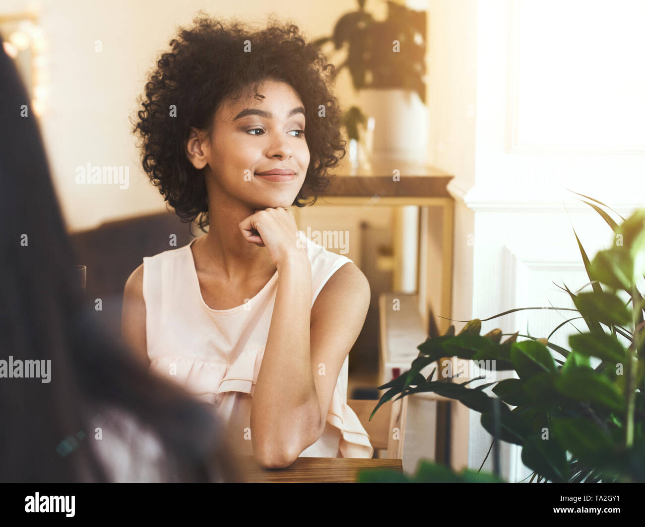 Träumen afrikanische amerikanische Mädchen sitzt im Cafe und bewundern Sie den Sonnenuntergang Stockfoto