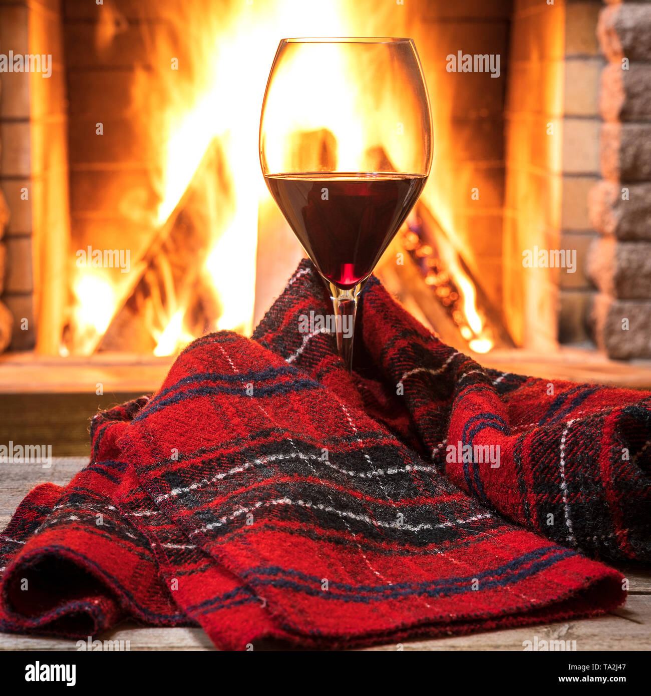 Glas Rotwein und warmer Schal gegen den gemütlichen Kamin Hintergrund, in Country House, horizontal, hygge, Home sweet home. Stockfoto