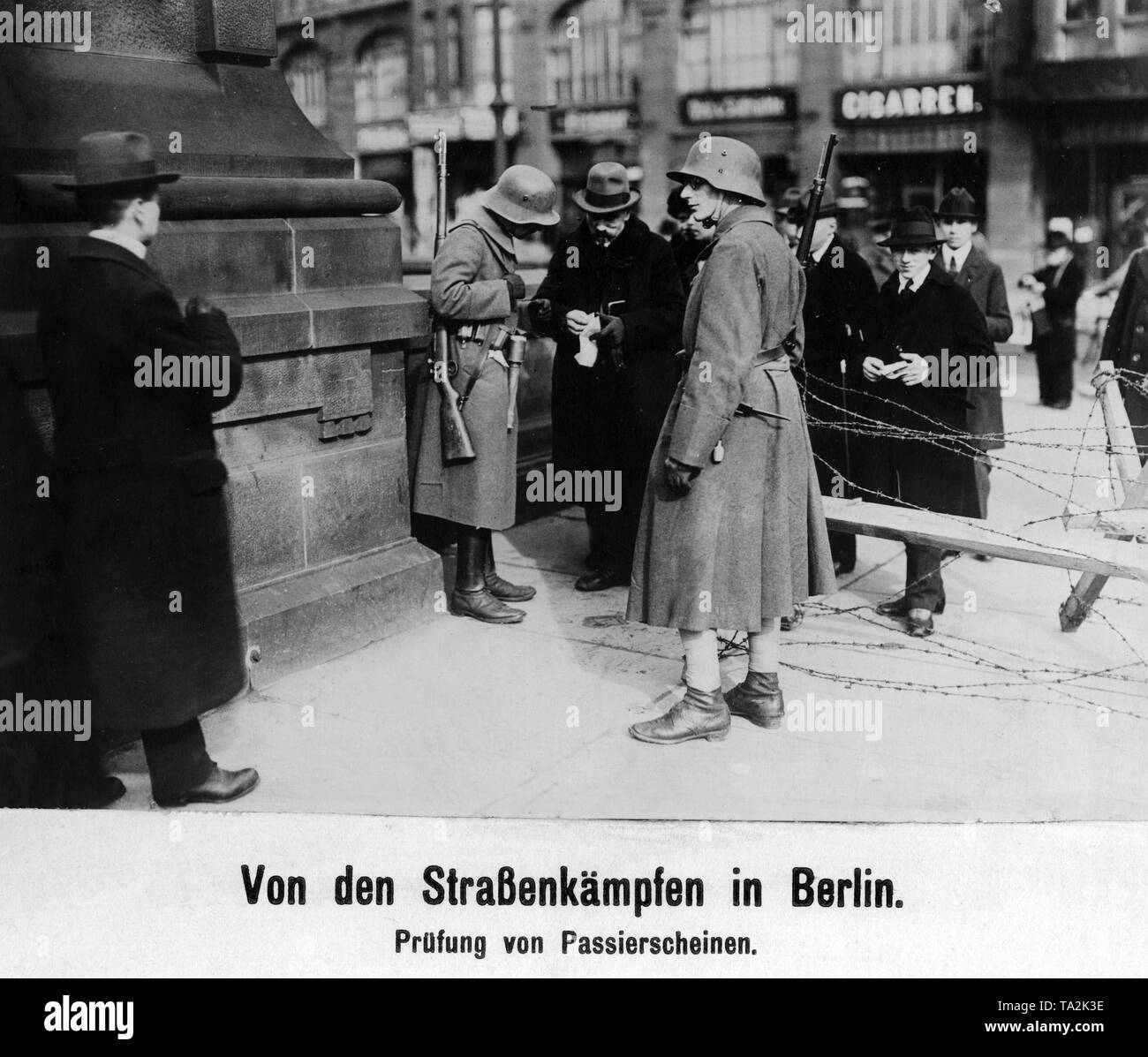 An einer Straße durch Regierungstruppen in Berlin blockiert, ein Soldat prüft die Genehmigung für ein Passant. Stockfoto