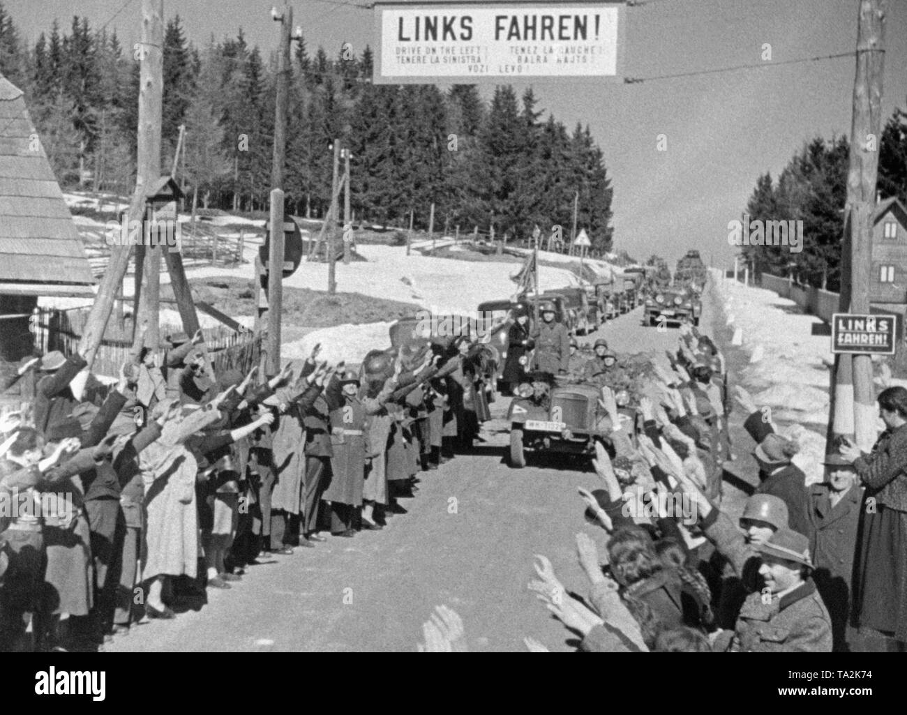 Die deutsche Wehrmacht Kreuze der österreichischen Grenze und ist von den Anwohnern begrüßt. Das Schild liest 'Drive auf der linken Seite!". In Österreich Menschen fuhren auf der linken Seite der Straße bis zur Annexion des Landes an das Deutsche Reich. Stockfoto