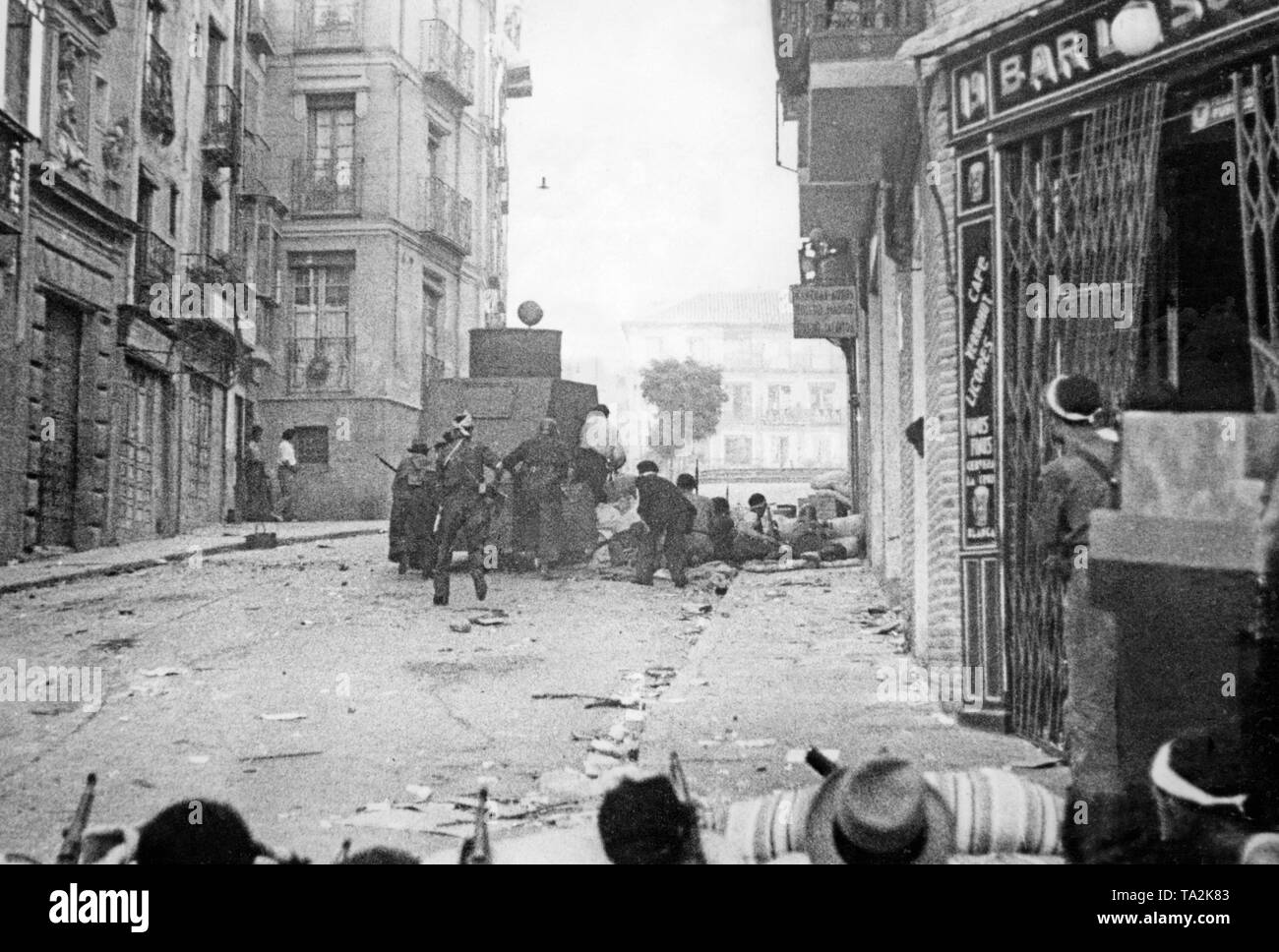 Republikanische Soldaten während der Belagerung der Alcazar von Toledo im Sommer 1936. Die Soldaten, die sich hinter einer Barrikade verschanzt haben, sind mit einem gepanzerten Fahrzeug abgedeckt. Stockfoto