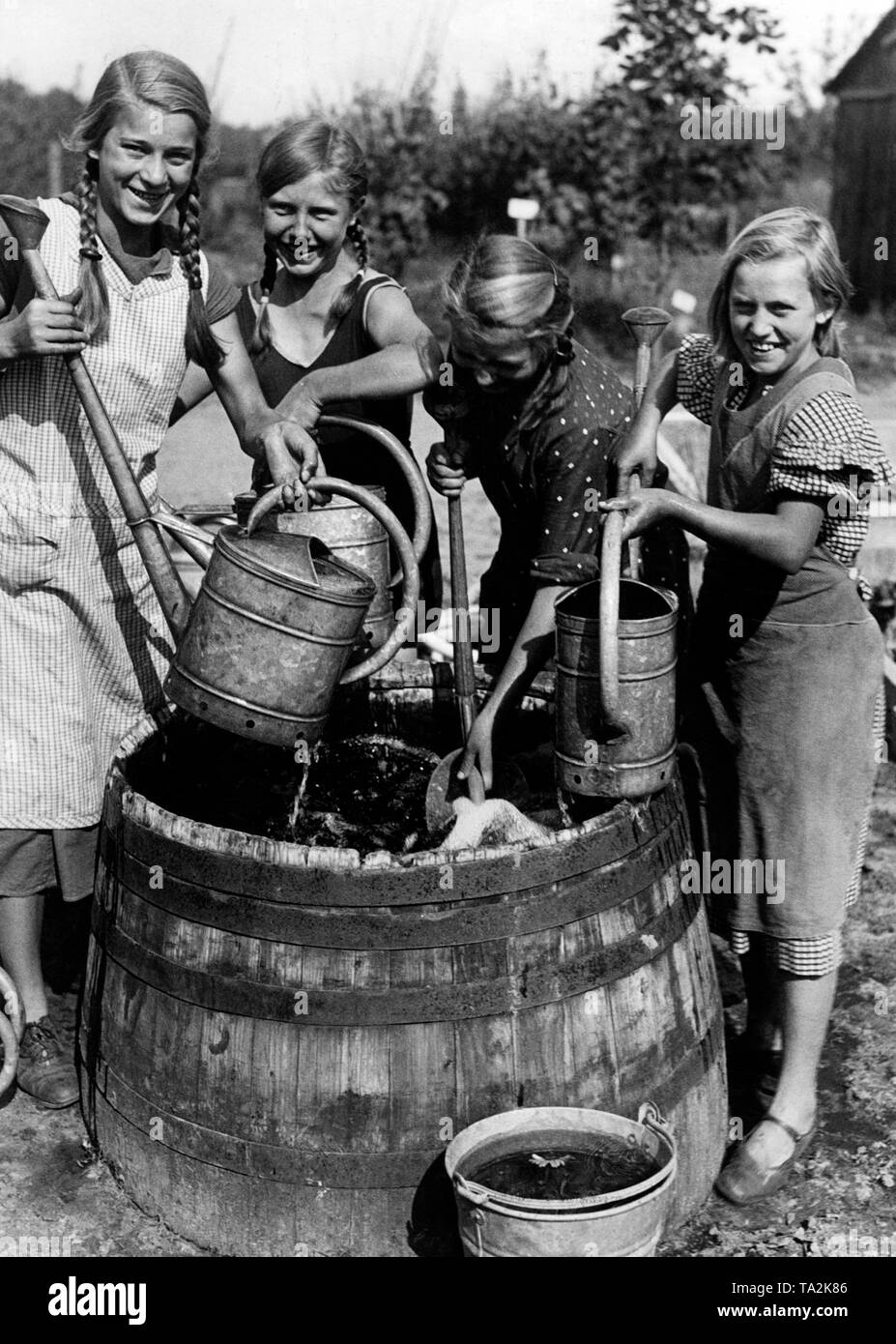 Landdienst Mädchen bringen Wasser mit giesskannen auf den Kindergarten von ihren Landjahrheim (Landschaft Internat). Stockfoto