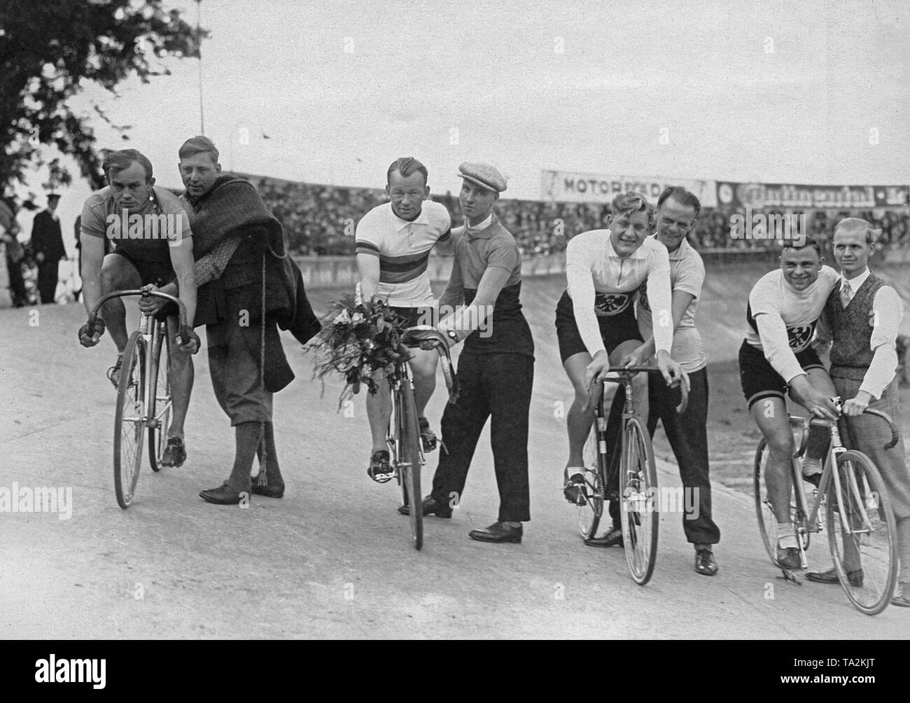 Vier Titel Radfahrer stehen mit ihren Helfern auf der Olympiabahn in Berlin. Von links: Helge Harder, Willi Gerwin, Hans Dasch und Willi Frach. Im Hintergrund und Tribünen. Stockfoto