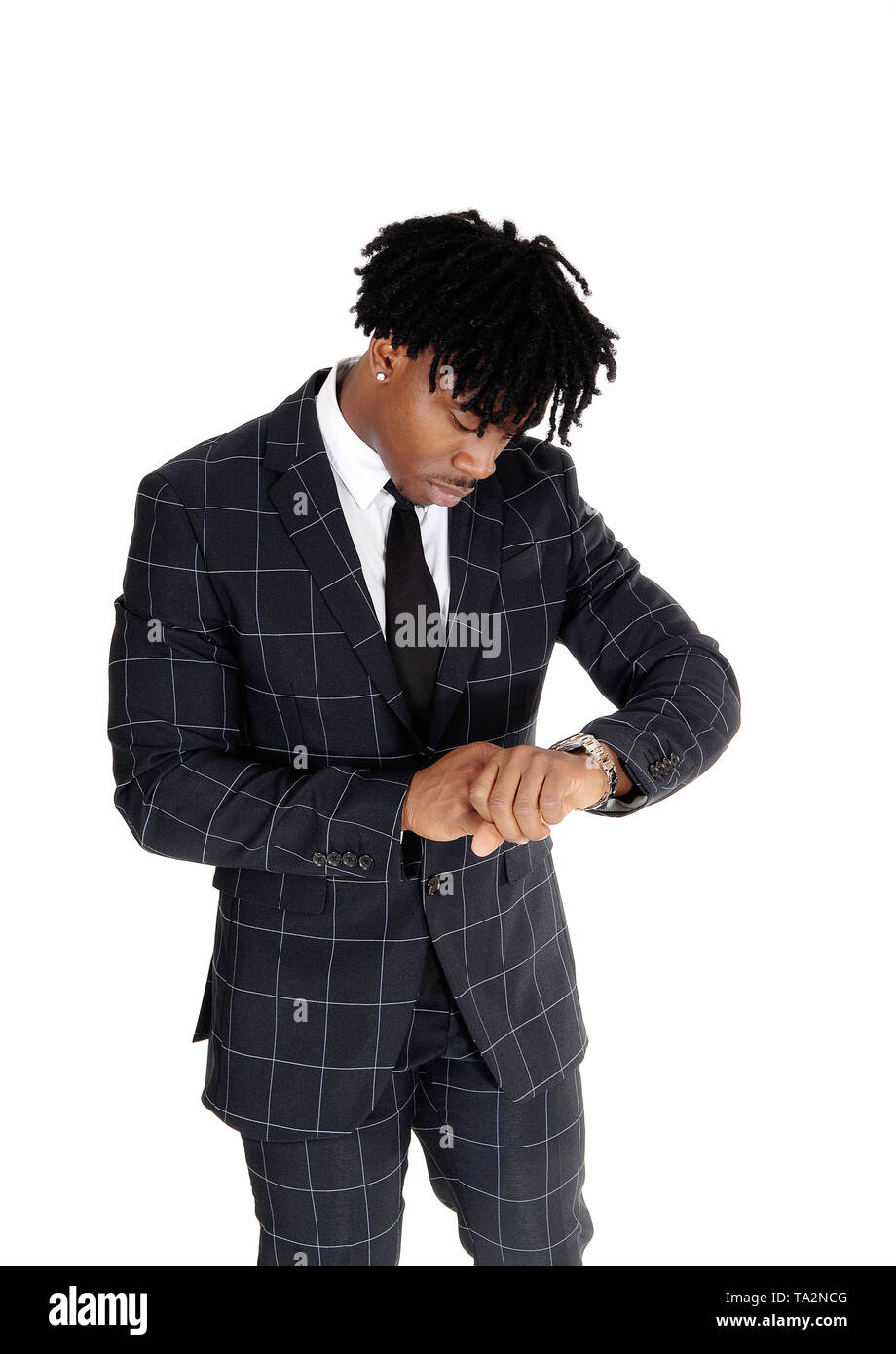 Ein Afroamerikanischer junge Mann in einem dunklen Anzug und weißes Hemd und Krawatte, zu der Zeit auf seine Armbanduhr suchen, auf weißem Hintergrund Stockfoto