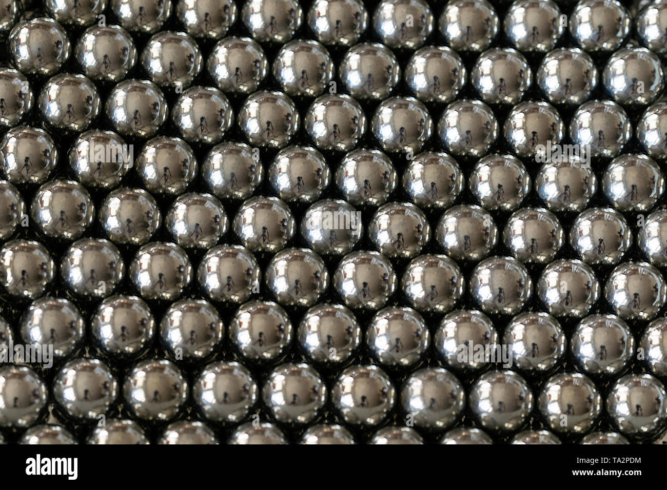 Close-up und Perspektive mit der Verwischung der viele Objekte bilden eine geordnete Struktur. Metall glänzenden Kugeln aus einer Schlinge schießen, gleichmäßig angeordnet. Stockfoto