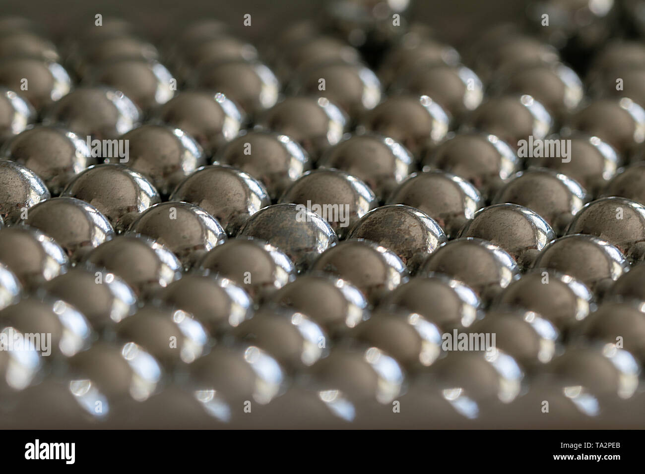 Close-up und Perspektive mit der Verwischung der viele Objekte bilden eine geordnete Struktur. Metall glänzenden Kugeln aus einer Schlinge schießen, gleichmäßig angeordnet. Stockfoto