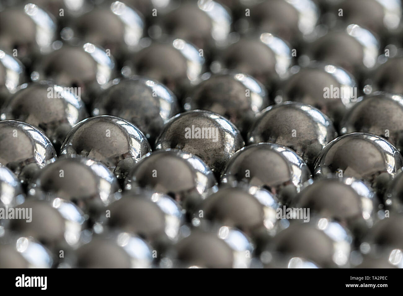 Close-up und Perspektive mit der Verwischung der viele Objekte bilden eine geordnete Struktur. Metall glänzenden Kugeln aus einer Schlinge schießen, gleichmäßig angeordnet. Stockfoto