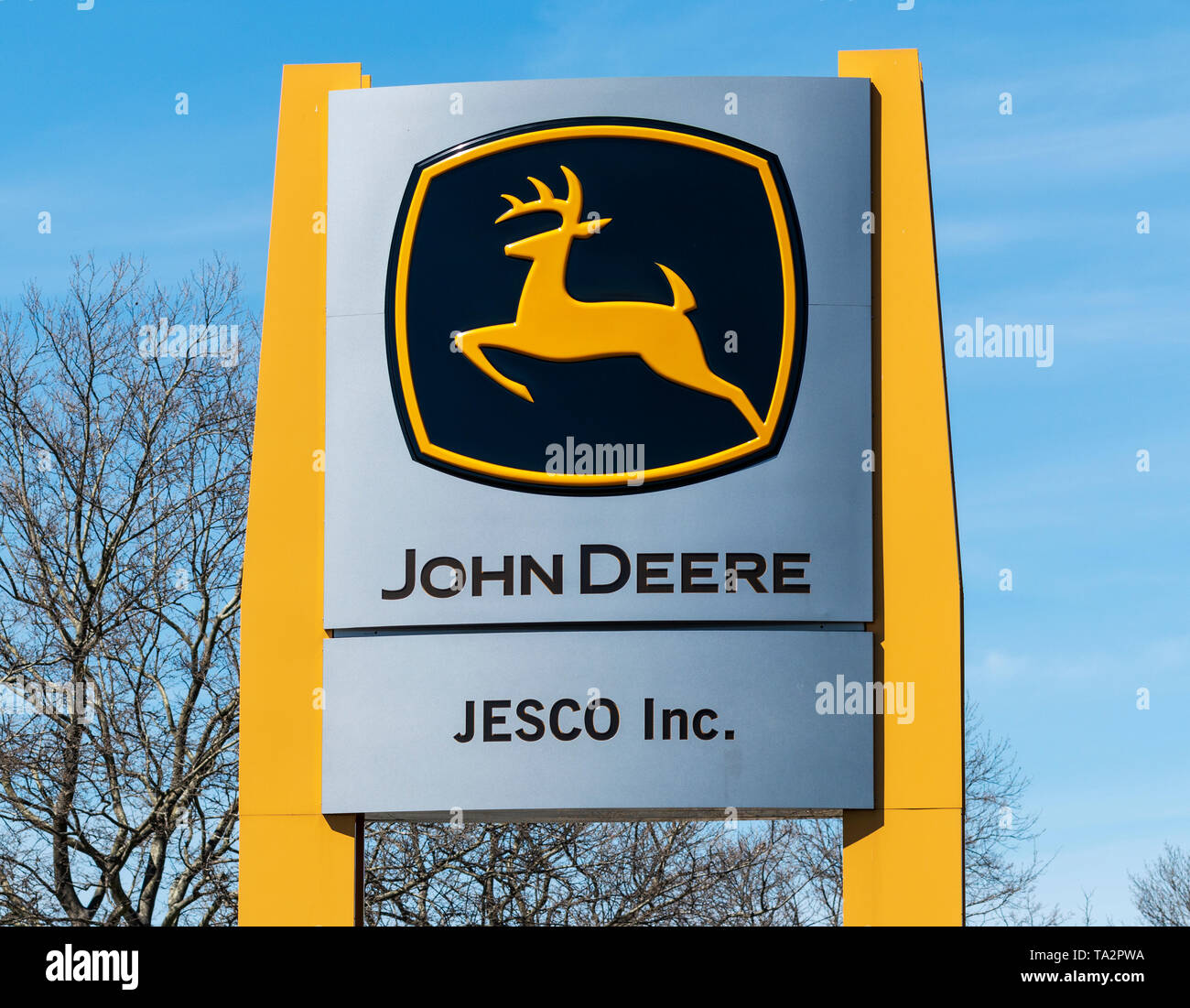 Deer Park, New York, USA - 17. April 2019: gold John Deere Zeichen mit einem blauen Himmel im Hintergrund Vor einem Büro. Stockfoto