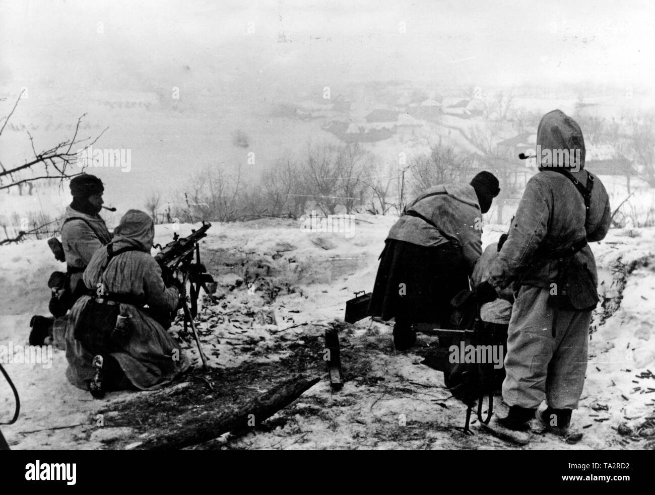 Ein Maschinengewehr 34 ist auf einem Hügel gebaut. Die Schnee-bedeckten Boden mit Messing übersät ist, und ein Soldat, raucht eine Pfeife. Dies deutet auf eine Pause in den Kämpfen. Foto der Propaganda Firma (PK): kriegsberichterstatter Lang. Stockfoto