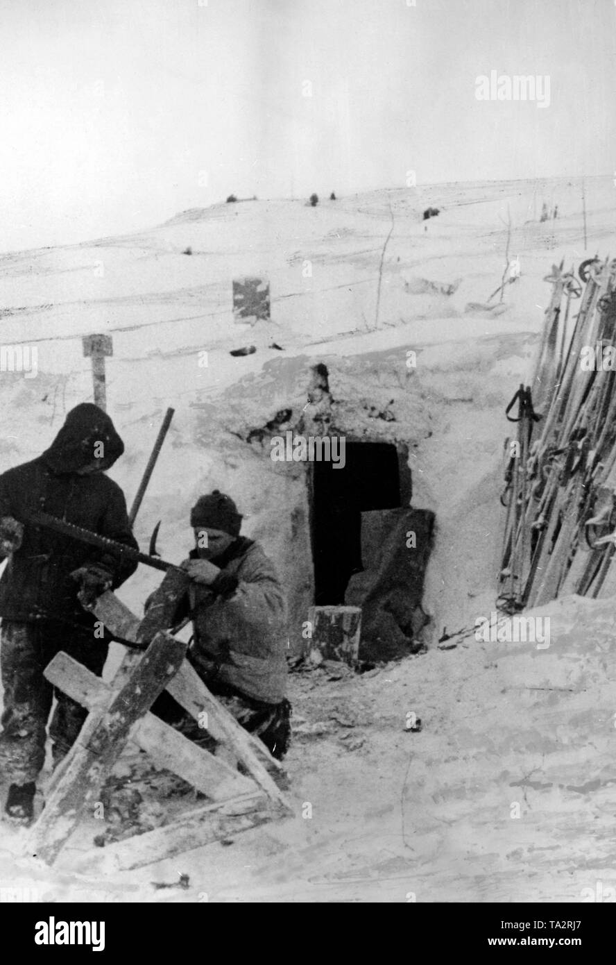 Zwei Berg troopers sah Holz vor ihren schneebedeckten Bunker. Foto der Propaganda Firma (PK): kriegsberichterstatter Reitzner. Stockfoto