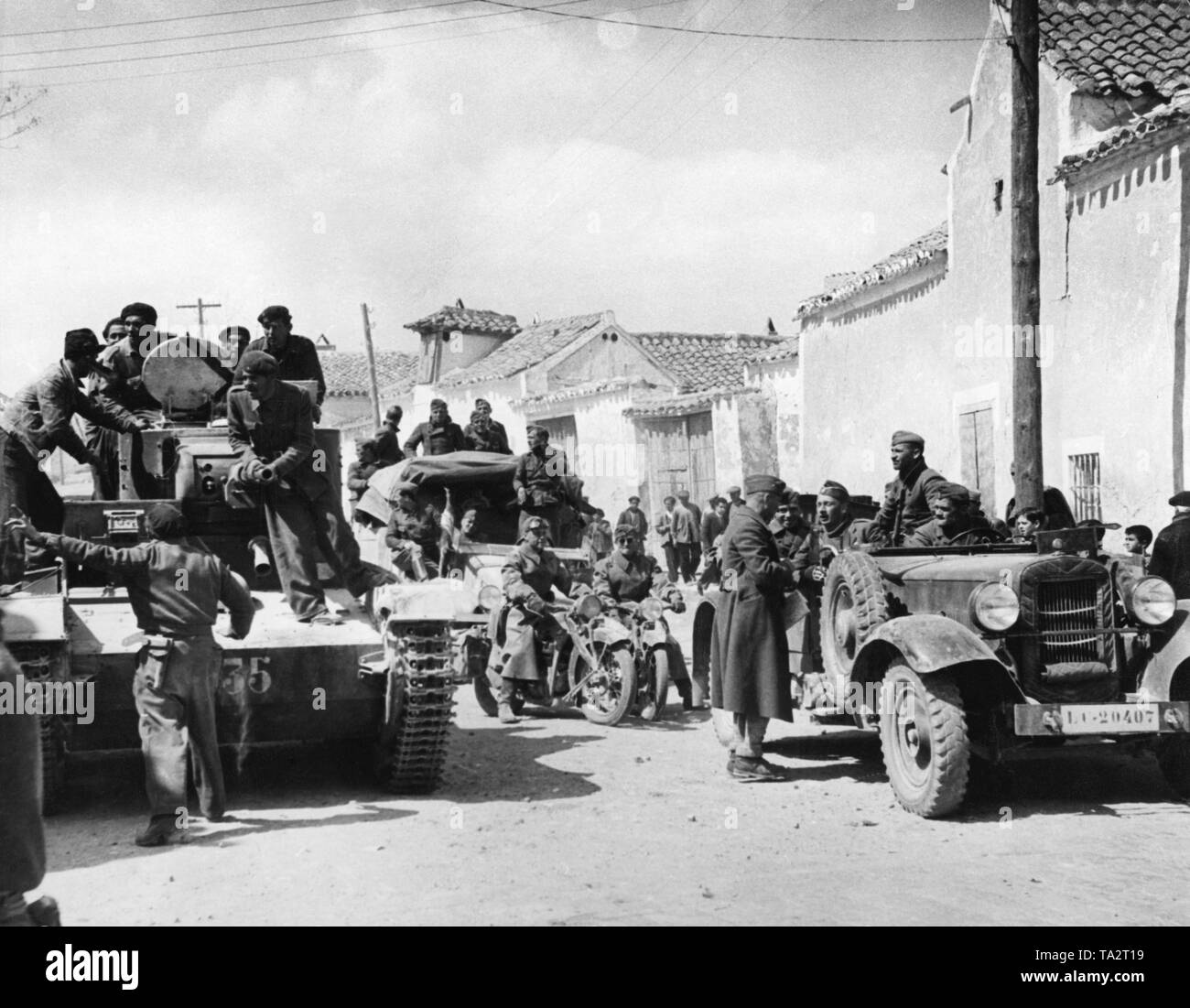 Ein spanischer Staatsangehöriger Tank (links, einen Beschlagnahmten russische T-26) und eine motorisierte Deutsche Einheit der Legion Condor (rechts, ein Mercedes-Benz 260 hinter, krads) das Dorf in der Nähe von Toledo Templique eindringen, Castilla La Mancha, die während der letzten Schlachten des Spanischen Bürgerkrieges am 29. März 1939. Stockfoto