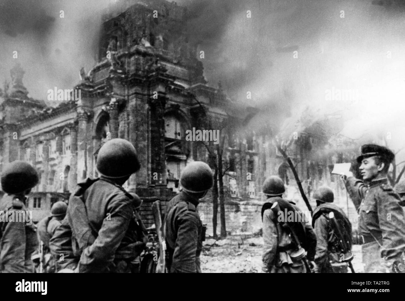Ein russischer Offizier spricht mit den Soldaten vor der brennenden Reichstag am Tag ihrer Erstürmung durch sowjetische Truppen. Stockfoto