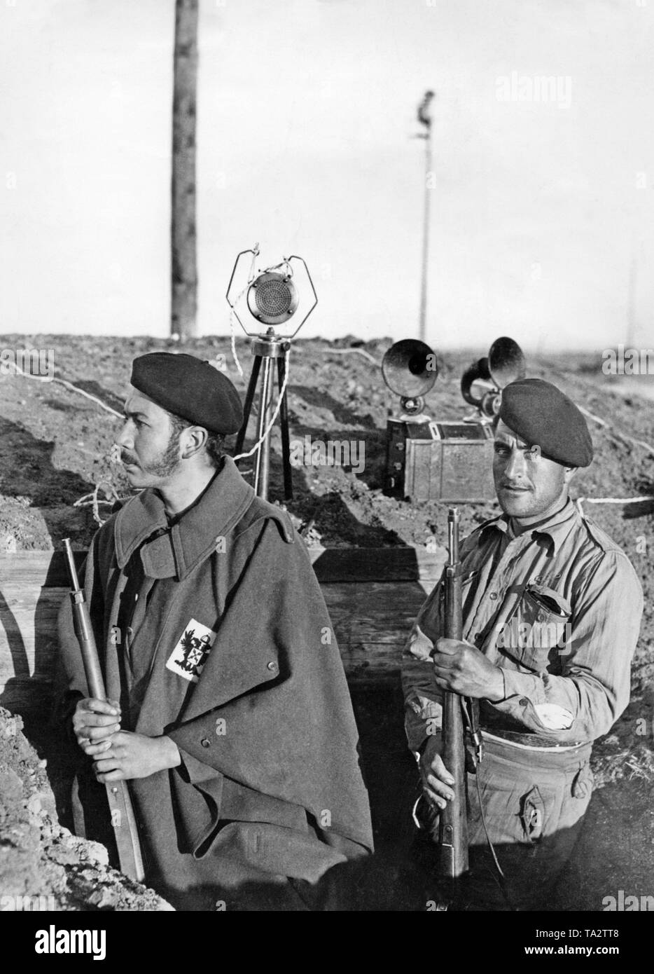 Foto von zwei wagenliste requete Kämpfer auf der Seite der Spanische Nationale Fraktion in einem Graben vor Madrid kämpfen im Dezember 1936. Der Kämpfer auf der linken Seite trägt die Kennzeichnung der Carlists, das Kreuz von Burgund. Im Hintergrund ist ein Mikrofon. Stockfoto