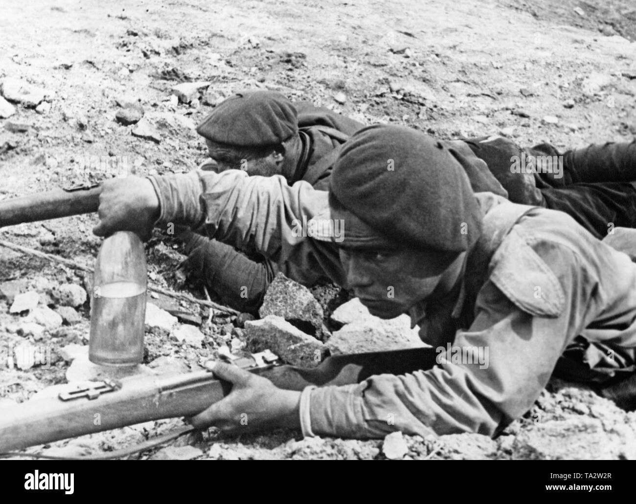 Zwei spanische Soldaten sind, werfen ein Gas-Flasche auf einen Tank, die dann mit Hilfe einer Granate auf der Vorderseite des Spanischen Bürgerkriegs in der Nähe von Madrid verbrannt wurde gefüllt. Der Soldat in der Front ist mit einem Gewehr Mauser System scharfgeschaltet ist. Stockfoto
