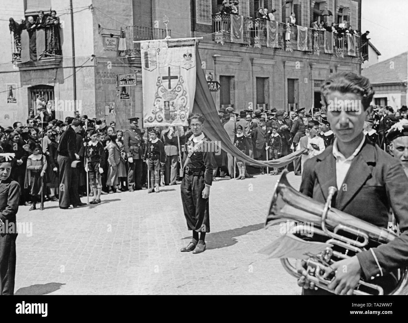 Foto der Hauptplatz von Valmaseda (30 km südwestlich von Bilbao), Baskenland, Spanien, im Sommer 1937. Hier sind die jungen Mitglieder einer christlichen Gruppe mit einem Banner und Instrumente. Im Hintergrund, Dorfbewohner, sowie Kinder, beobachten die Szene. Ein paar Tage zuvor, im Juni 1937, Bilbao wurde erobert und fiel auf den spanischen nationalen Fraktion. Stockfoto