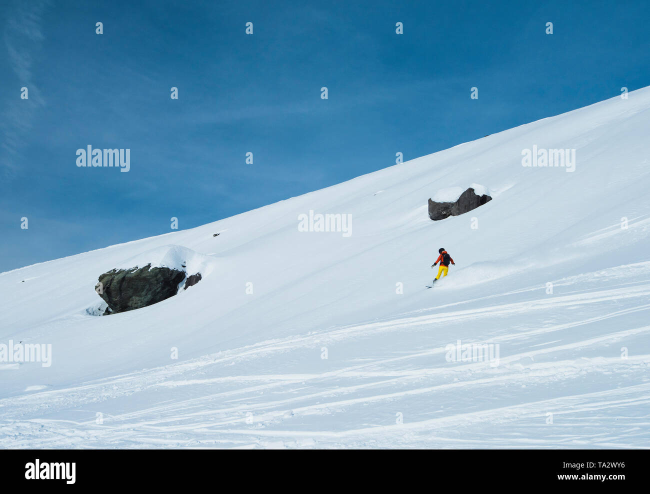 Panoramablick auf die Landschaft mit off piste Skifahrer hinunter Hang im Winter Alpine Mountain Resort Stockfoto