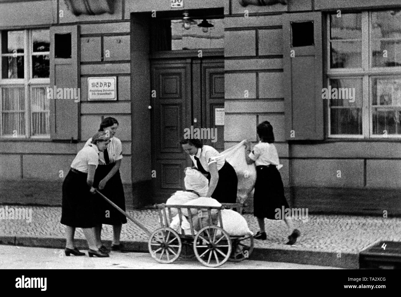 Film Szene aus dem UFA Dokumentarfilm "Helfende Haende" ( "Helfende Hände"). BDM-Mädchen sind das Sammeln von Wertstoffen mit einem Auto, unter anderem spinnen Material. Hier, vor einem Gebäude der NSDAP/AO. Stockfoto