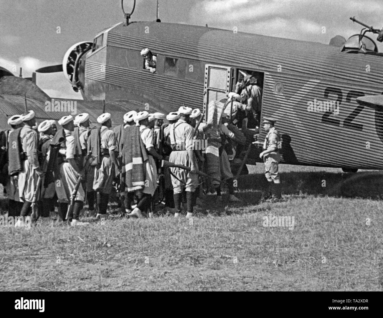 Das Foto zeigt die marokkanische Soldaten der spanischen Fremdenlegion mit einem deutschen Junkers Ju 52 Transportflugzeuge mit der Lackierung der Deutschen Legion Condor. Die Soldaten wurden von Tetouan, Spanish-Morocco, Afrika zu fliegen, auf dem Spanischen Festland im Sommer 1936. Auf der rechten Seite an der Oberseite, die On-board-Waffe (MG 34) gegen feindliche Kämpfer. Nach dem Ausbruch des Spanischen Bürgerkrieges am 27. Juli 1936 übermittelte Deutschland militärische Unterstützung für General Franco (Operation Feuerzeauber). Zusätzlich wurden 20 Ju-52 s (meist Lufthansa Flugzeuge) wurden bereitgestellt, die flogen mehr als 800 Flüge von Stockfoto