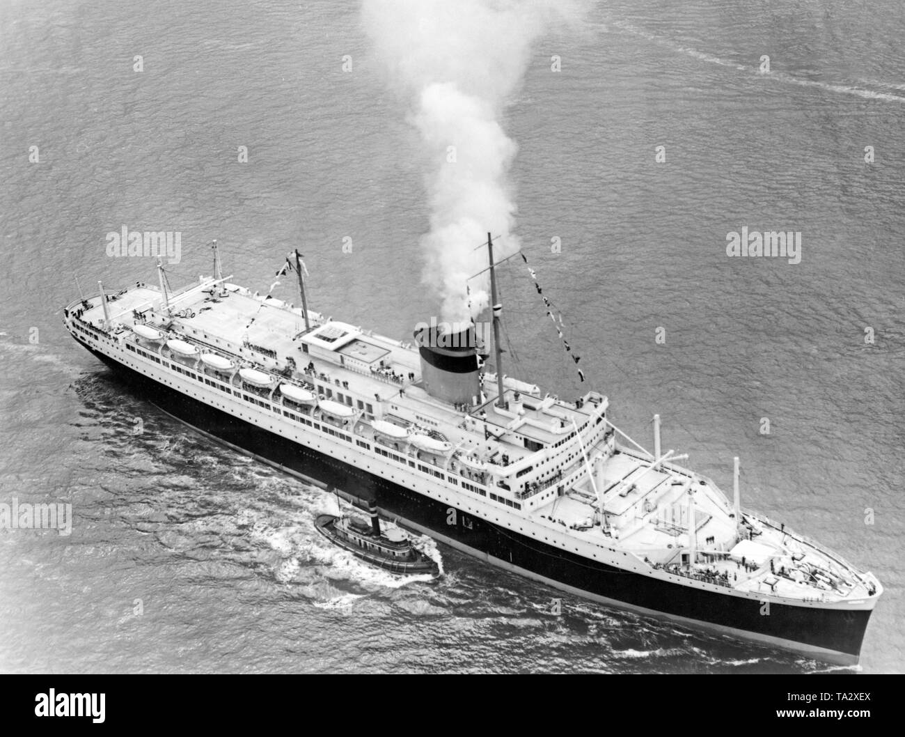 Die französischen Passagierschiff SS' Champlain" erreicht den Hafen von New York nach der Jungfernfahrt, von einem Schlepper begleitet. Stockfoto