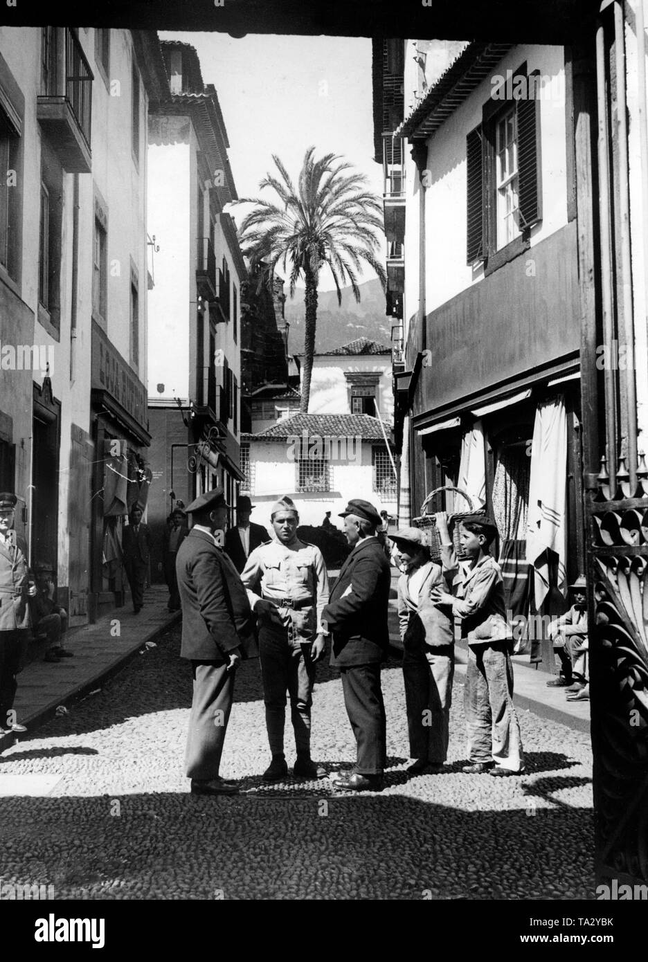 Urlauber der NS-Organisation "Kraft durch Freude" ('Stärke durch Freude") befinden sich in einem Gespräch mit einem portugiesischen Soldaten bei einem Besuch in Funchal, der Hauptstadt von Madeira. Stockfoto