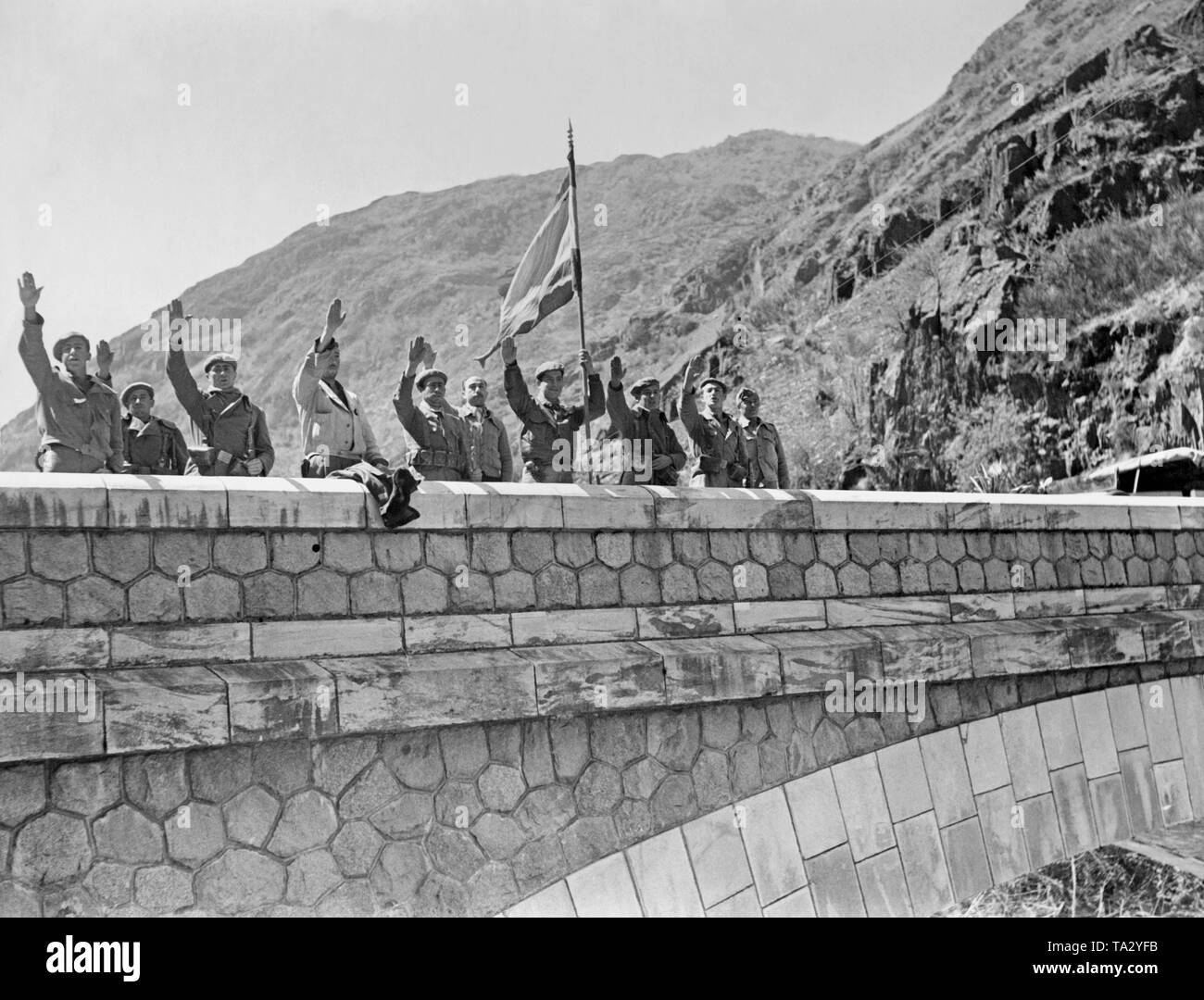 Soldaten der Franco Truppen auf der Brücke in der französischen Grenzstadt Val d'Aran in Katalonien, im Frühjahr 1938. Die soldaten Hoist eine spanische Flagge und die Arme in der faschistischen Gruß anheben. Stockfoto