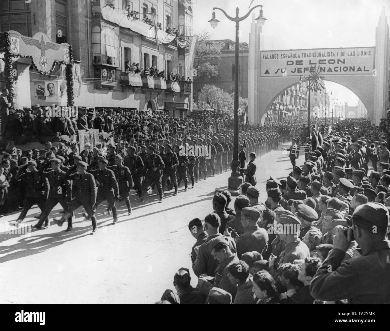 Foto von einer Einheit der Deutschen Legion Condor beim Marschieren auf einer Parade in der Stadt Leon, Kastilien und Leon am 22. Mai 1939. Im Hintergrund ist die Rückseite der Triumphbogen, die zu Ehren der deutschen Freiwilligen Union durch die Stadt von Leon gespendet wurde. Eintragung in Spanisch: Die spanische Falange von Leon begrüßt seine nationalen Führer. Stockfoto