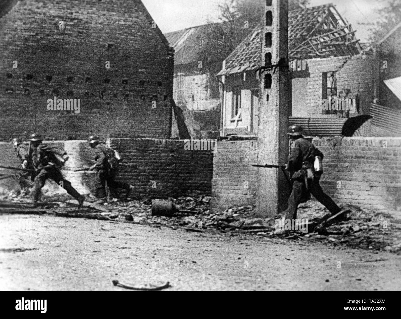 Eine Gruppe von Deutschen Infanteristen sind entlang einer Straße während der Kämpfe für ein französisches Dorf. Stockfoto