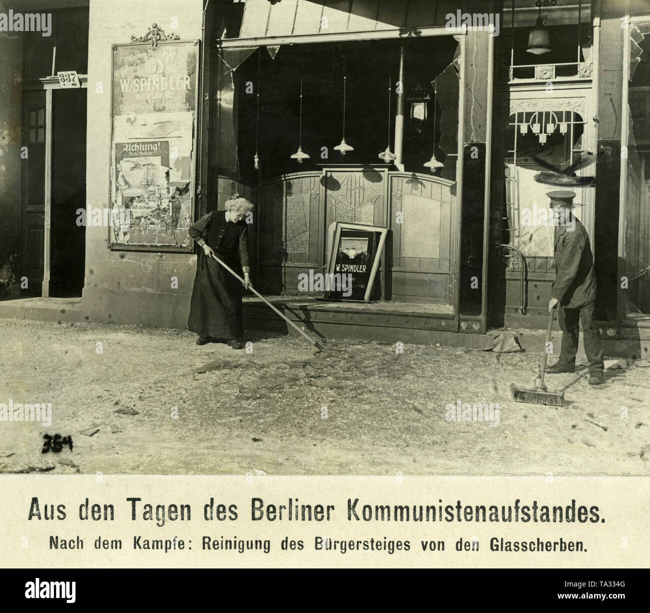 Ein Mann und eine Frau kehren Scherben vor dem Schaufenster eines Wäscheservice, die Wilhelm Spindler. Stockfoto